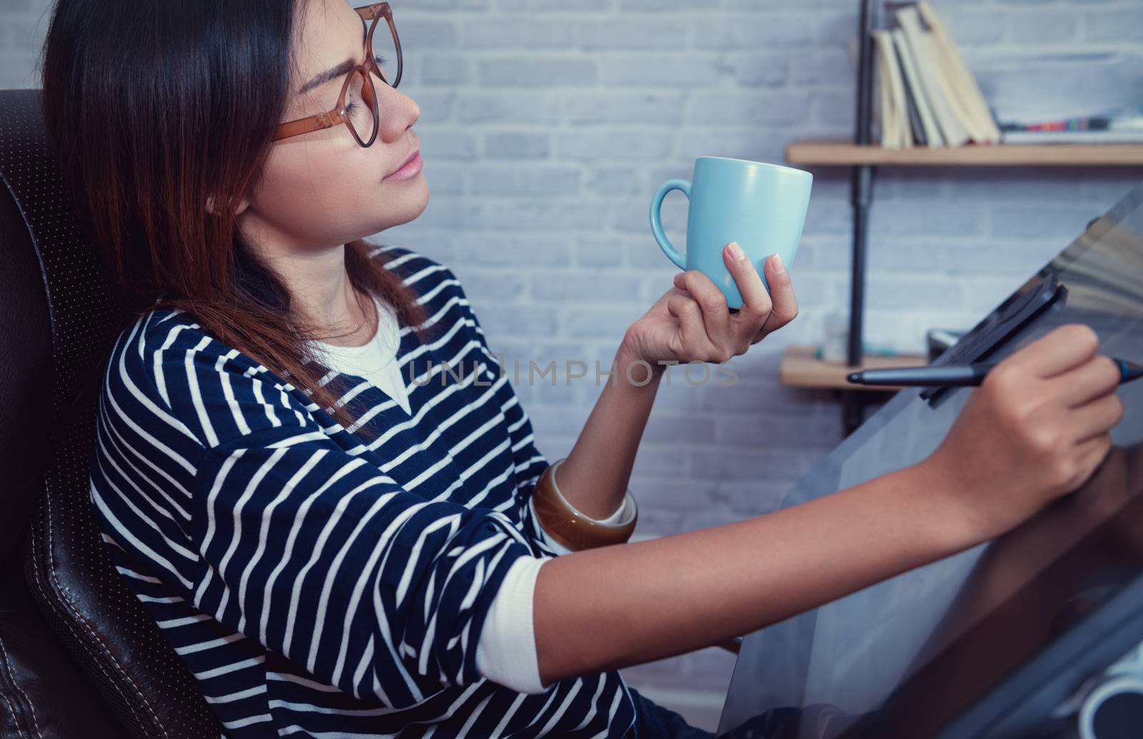 Asian woman looking down on a cup of coffee to sketch, focus on face