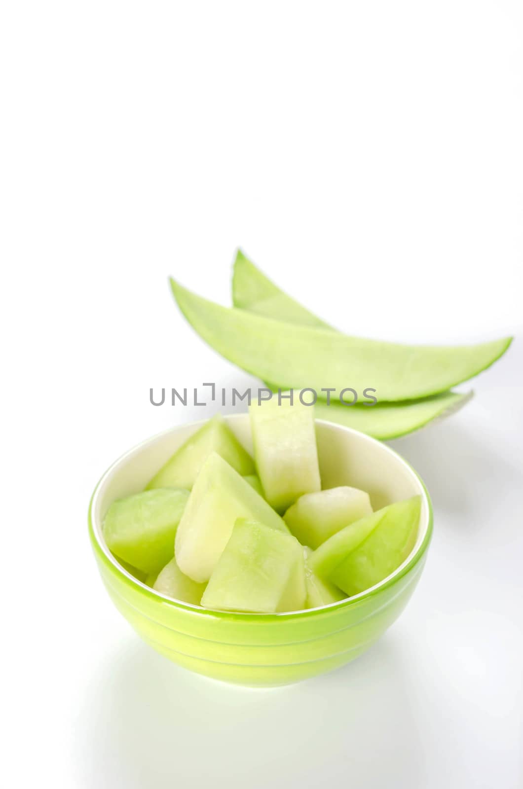 shopped green melon in bowl on white background