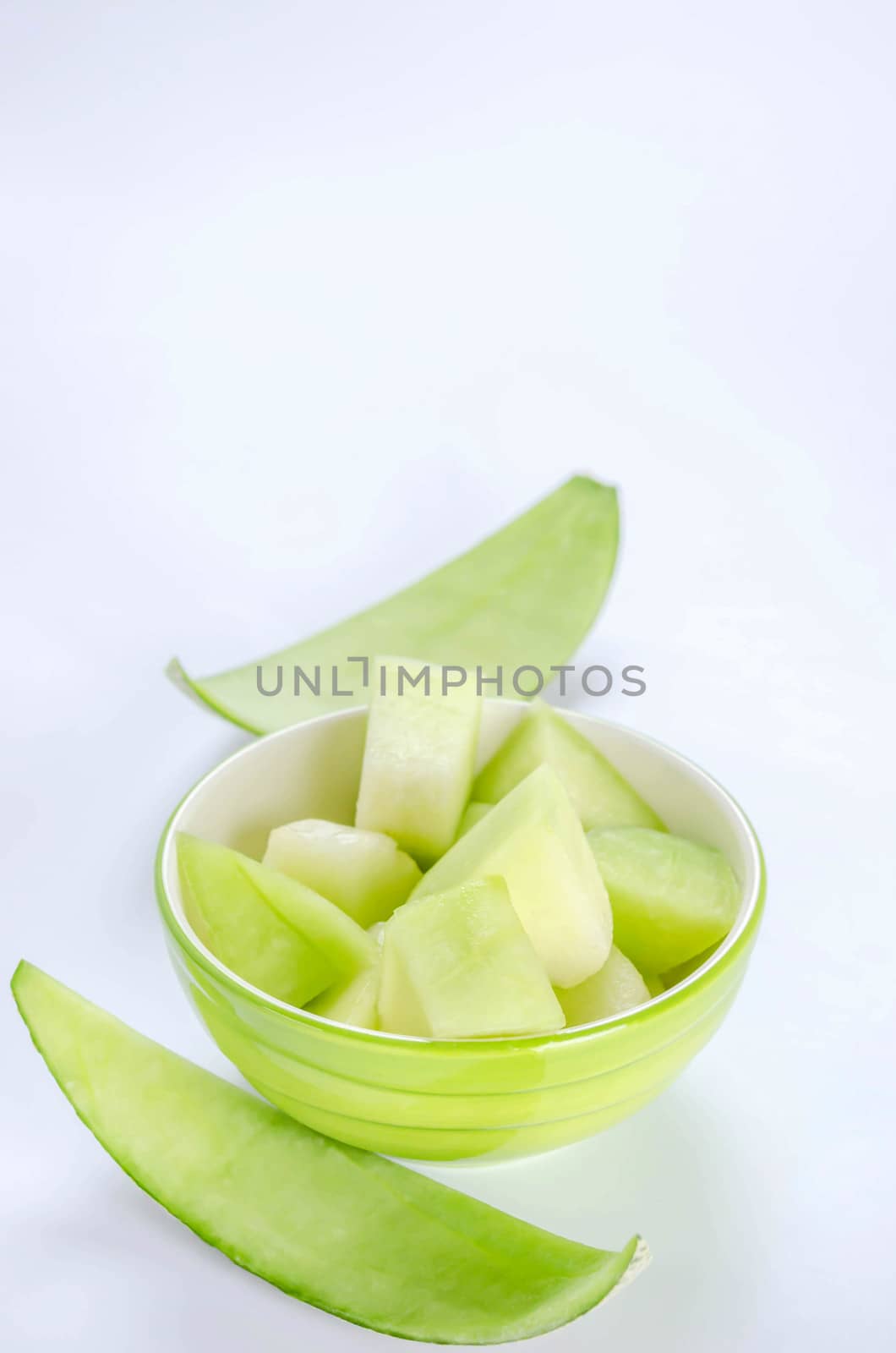 shopped green melon in bowl on white background