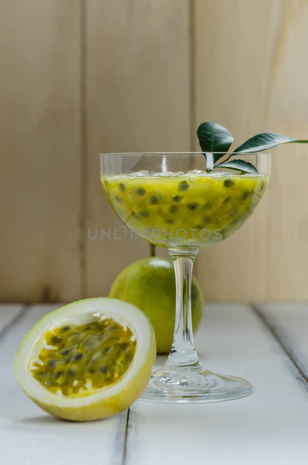 Fresh passion fruit juice in glass with passion fruits over wooden background , still life