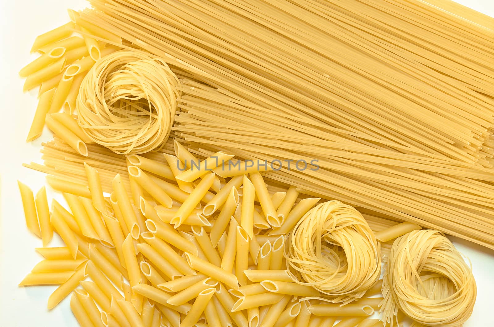 Different pasta lying on the white surface by Gaina