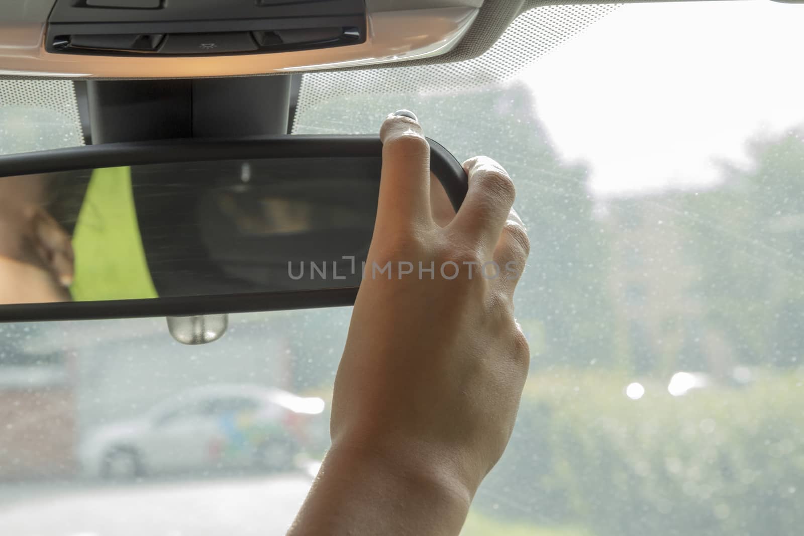 the girl in the car with beautiful manicure adjusts the rear view mirror