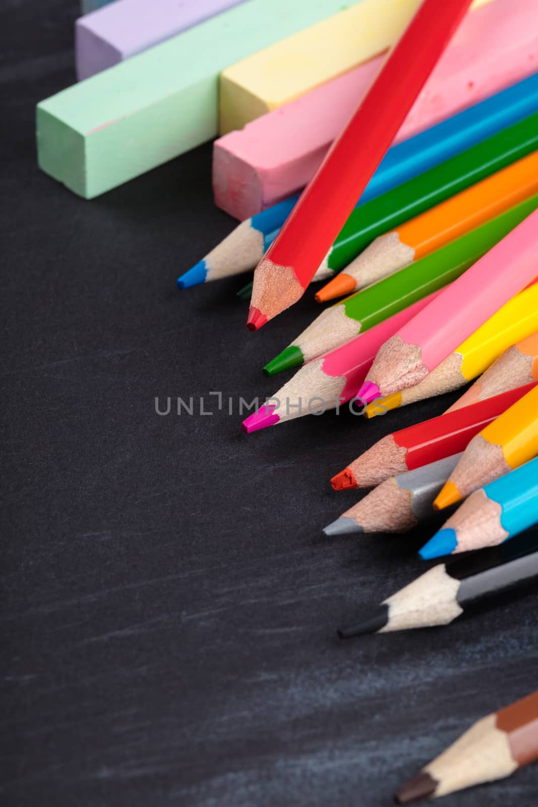 colored pencils and crayons on a black background
