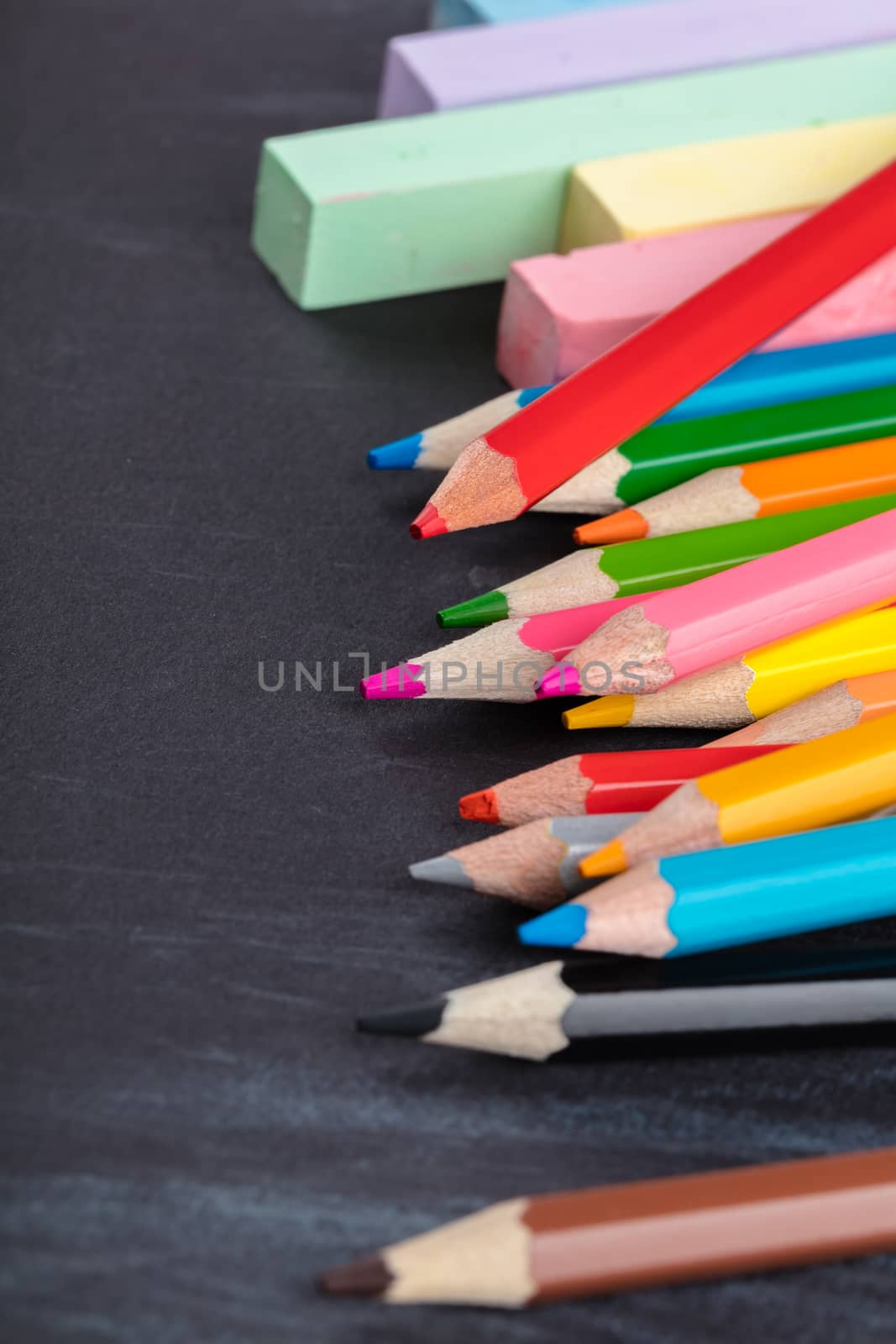 colored pencils and crayons on a black background