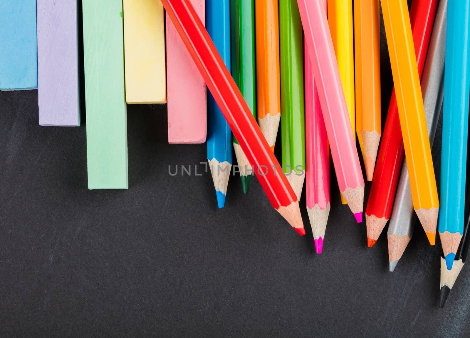 colored pencils and crayons on a black background