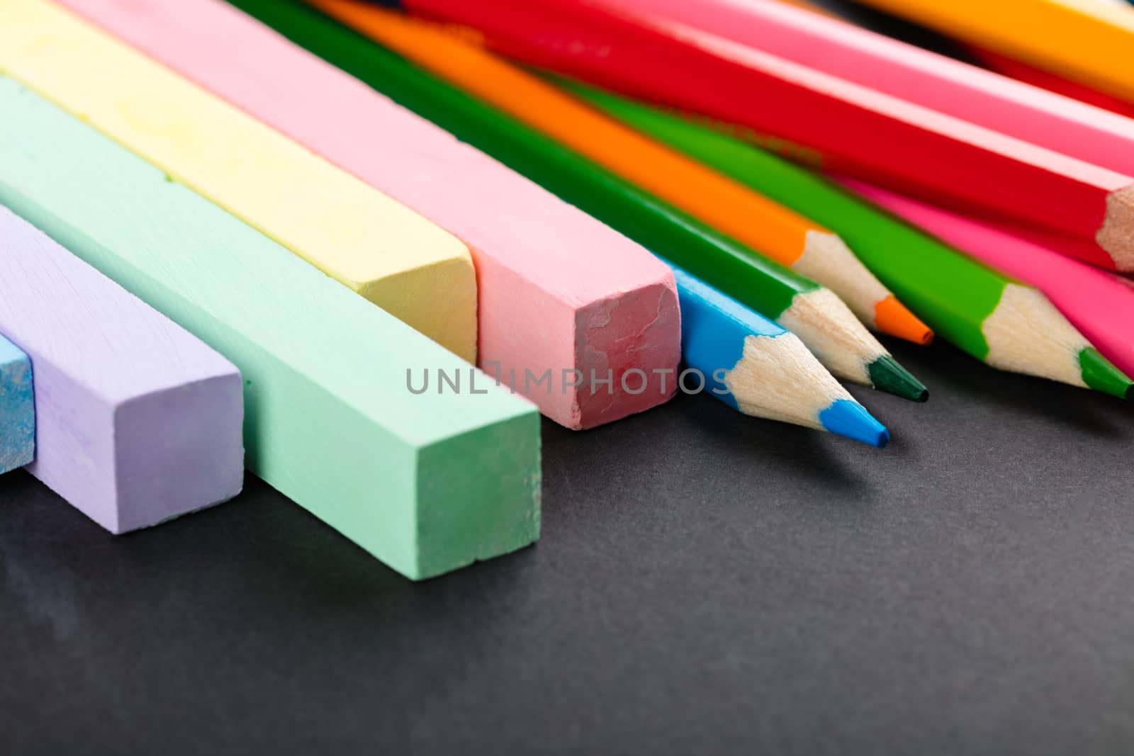 colored pencils and crayons on a black background