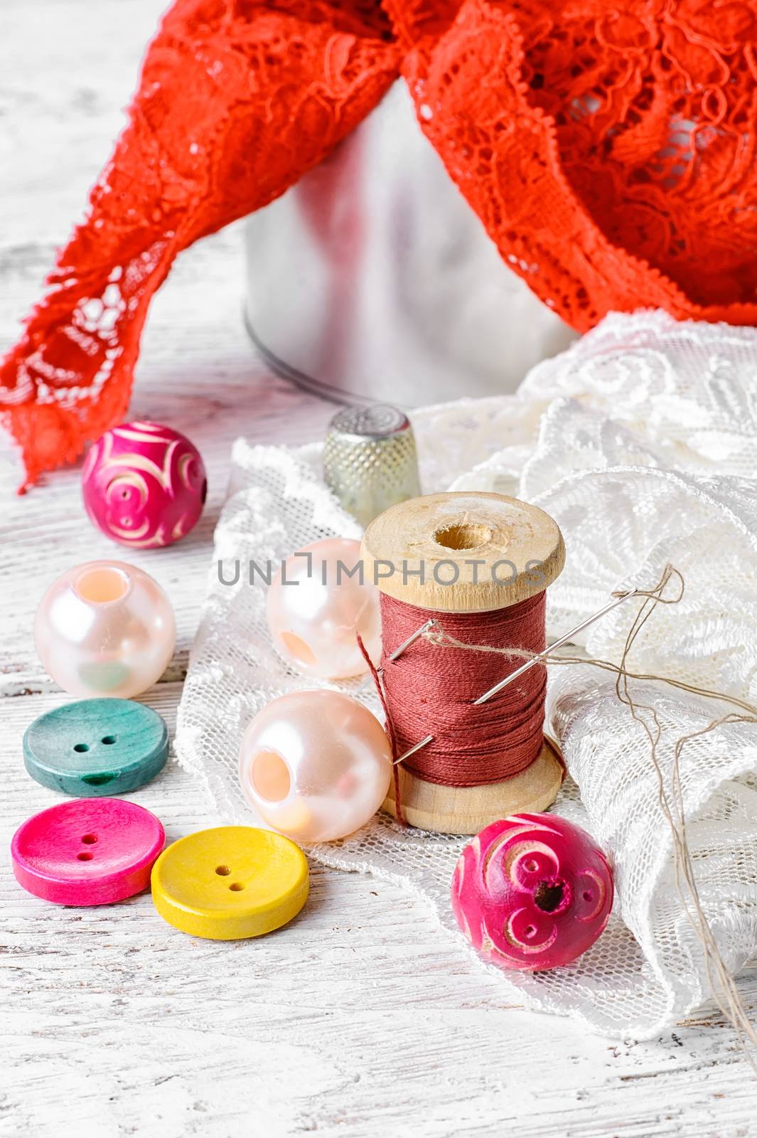 Fabric lace,bright colored buttons and thread on a light background