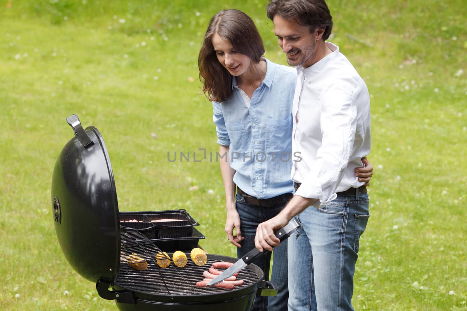 Happy couple cooking food on barbecue