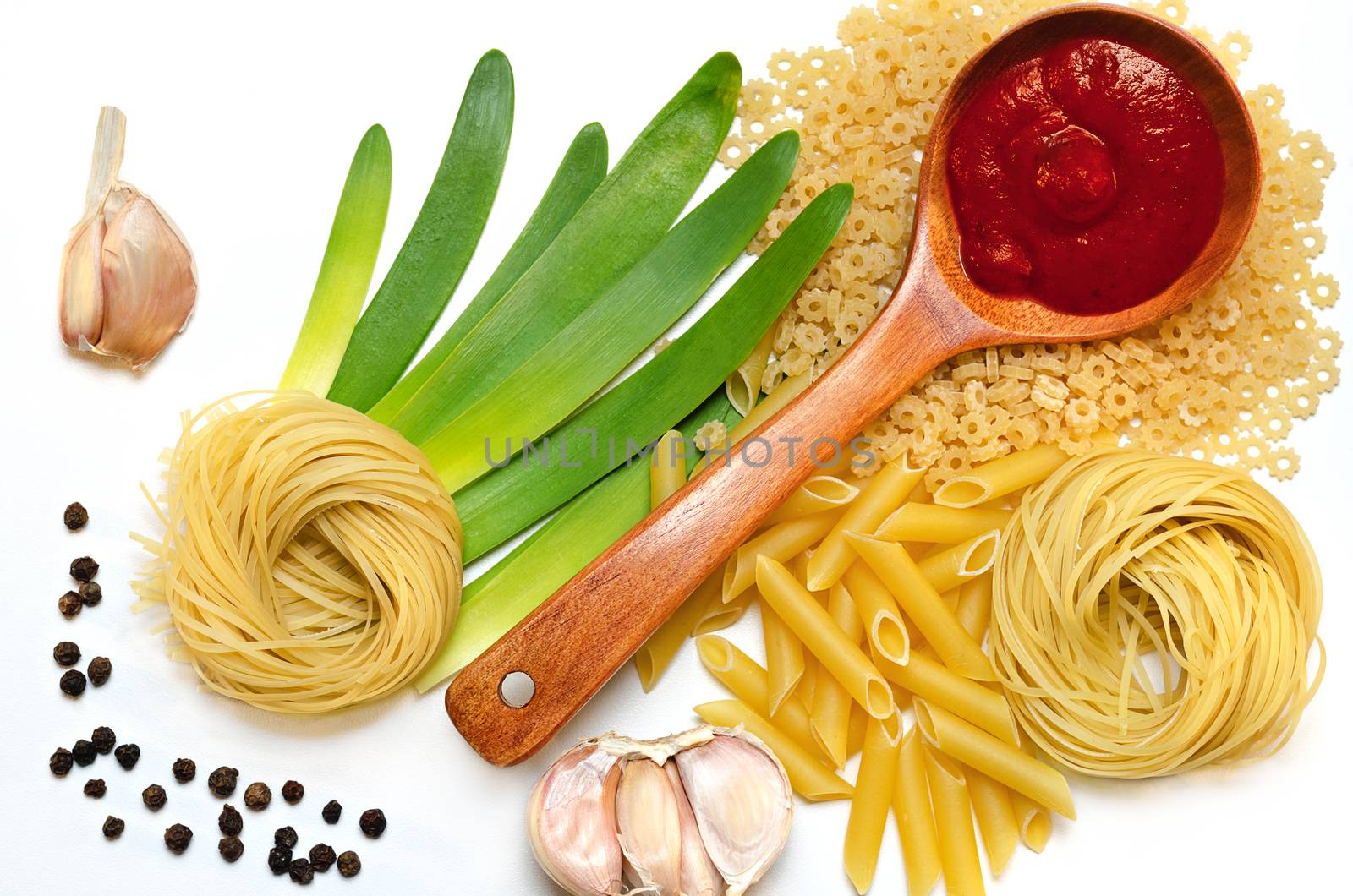 Different pasta and spices on white surface by Gaina