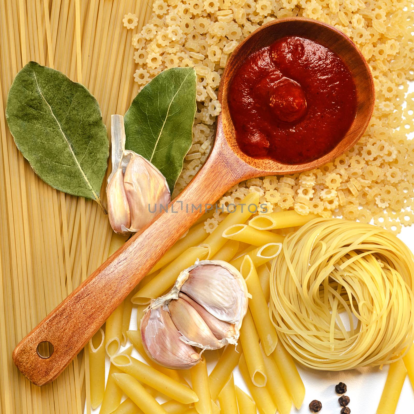 A variety of pastas, a wooden spoon of tomato ketchup and spices, top view.