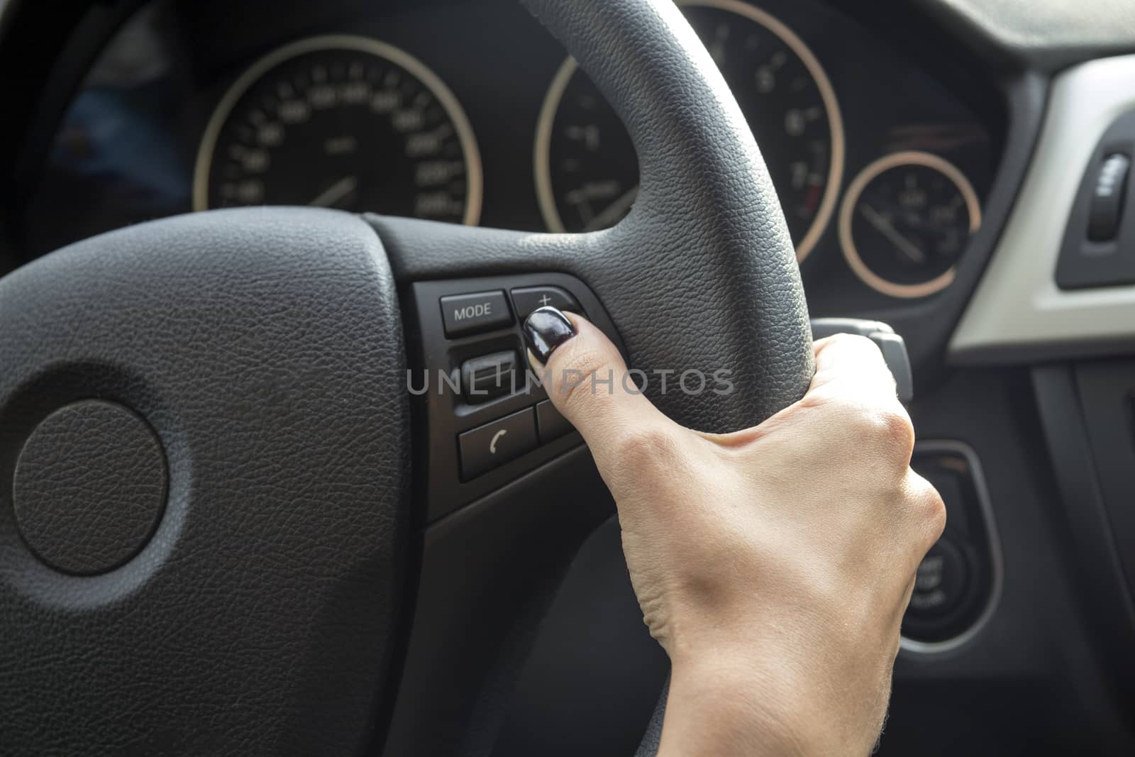 Arm girls with trendy manicure holds the steering wheel in the car.