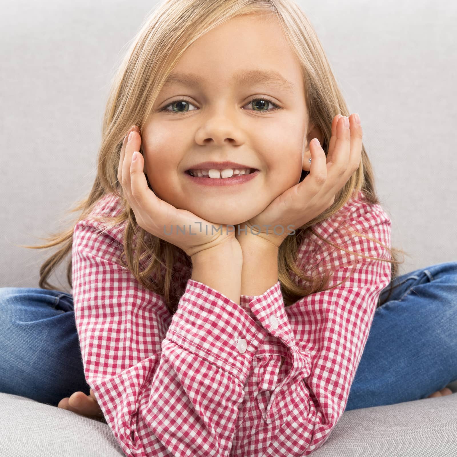 Little girl sitting on a couch and looking to the camera