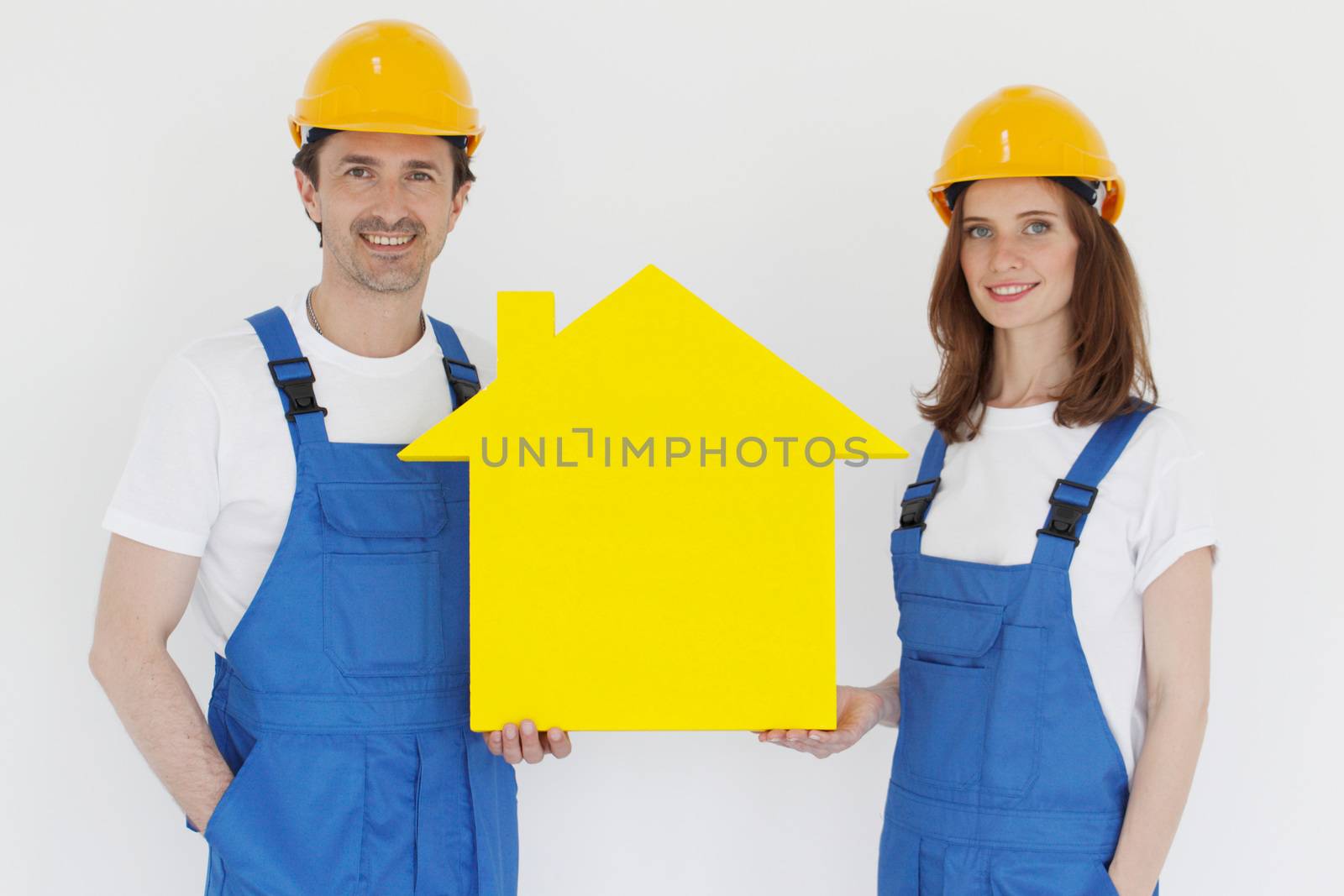 Happy smiling workers in hardhats holding house model