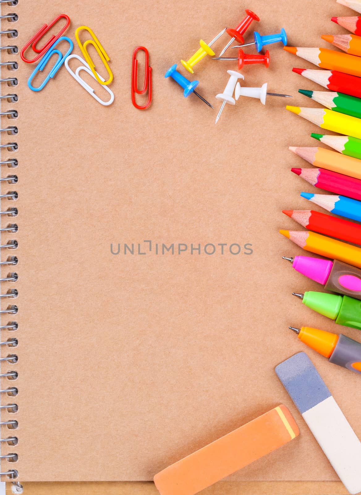 Notebook closeup with colored pencils, erasers, paperclips and buttons