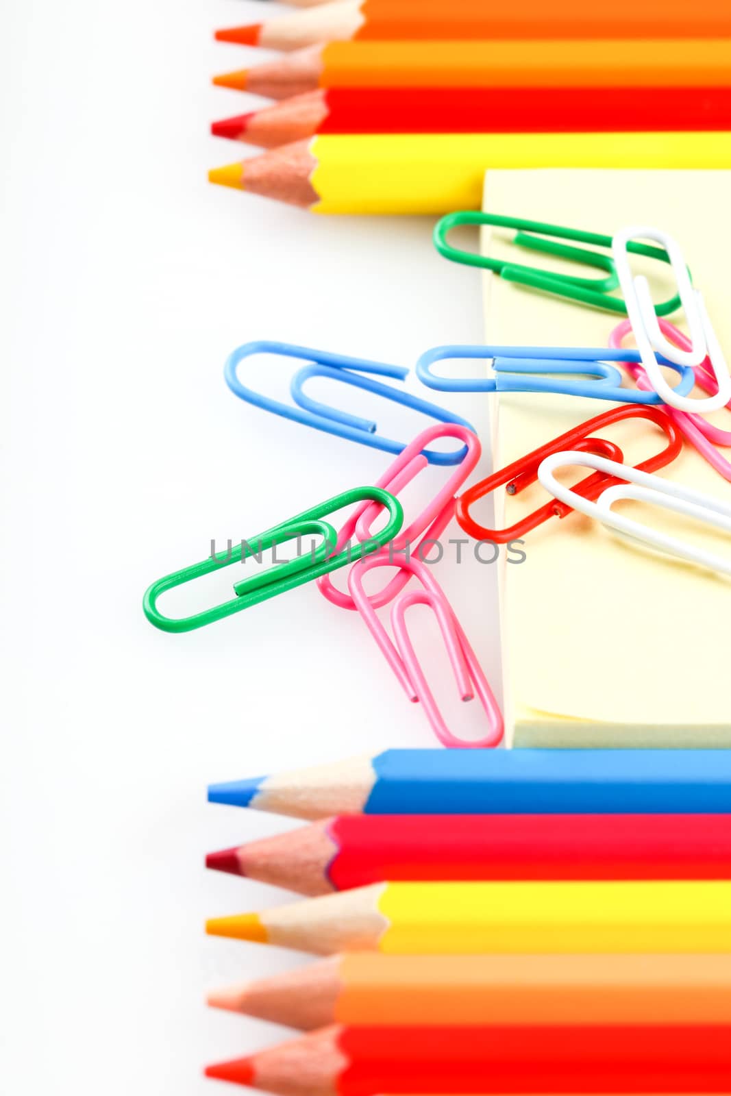 set of colored pencils and paper clips on a white background