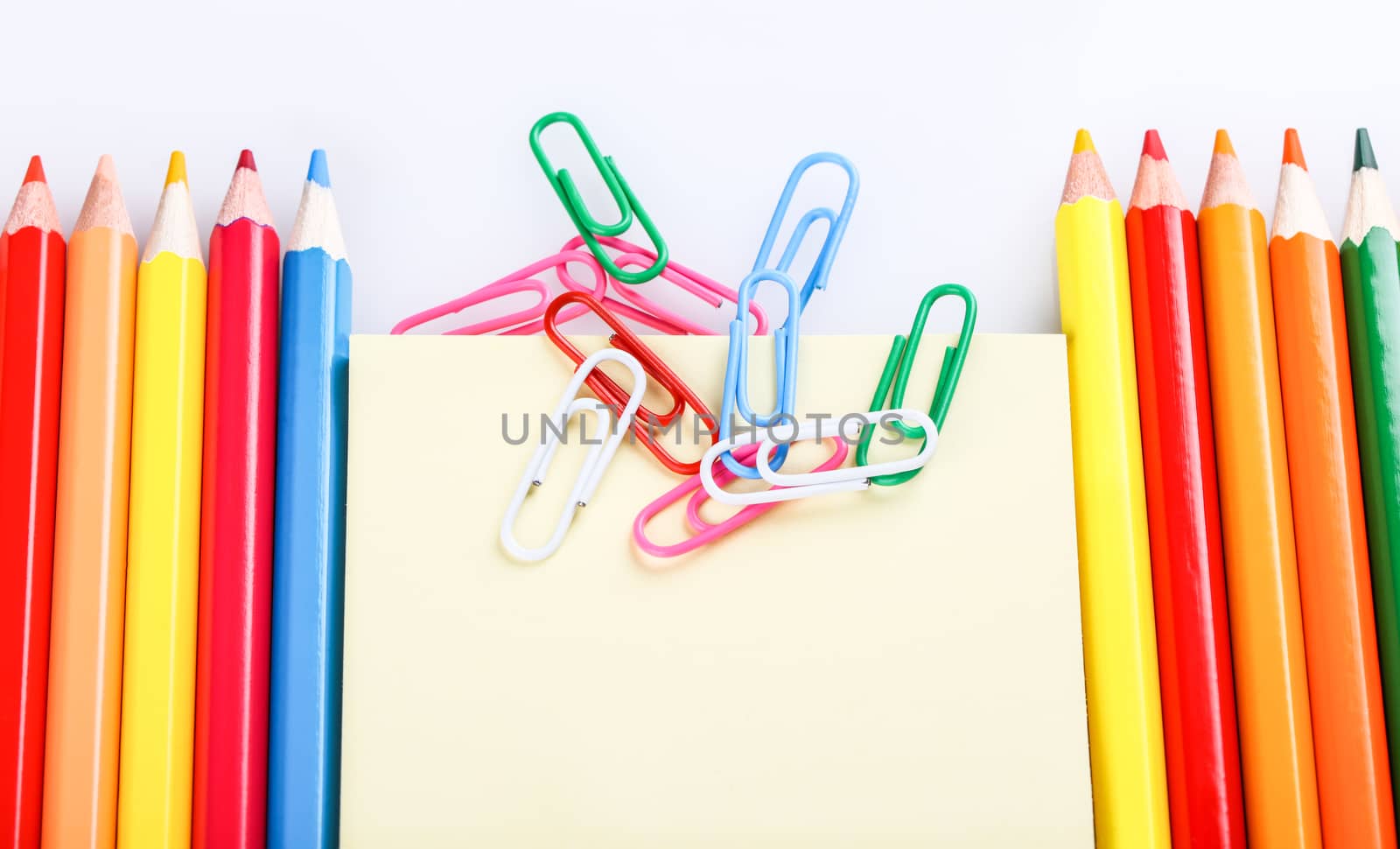 set of colored pencils and paper clips on a white background