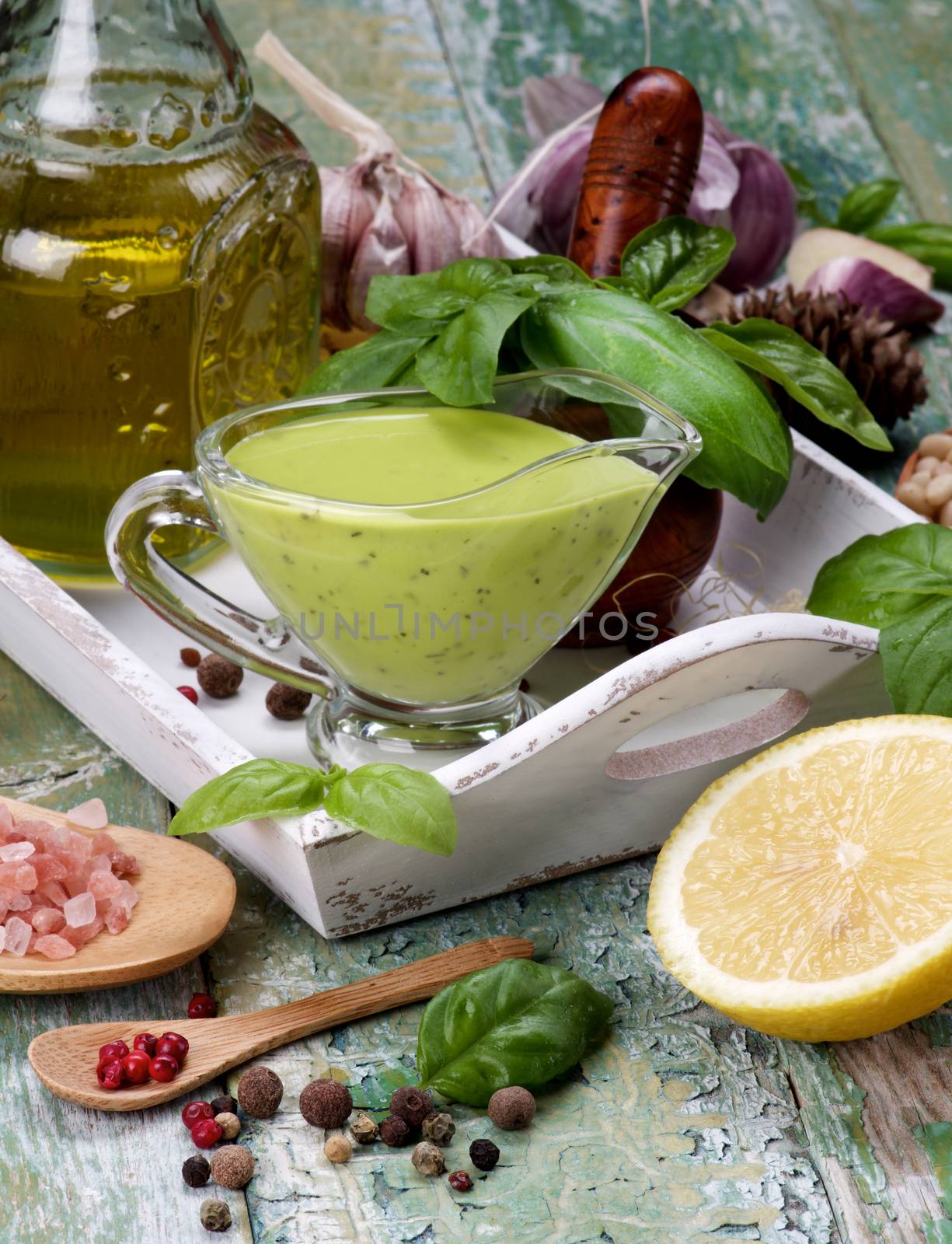 Freshly Made Creamy Pesto Sauce in Glass Gravy Boat with Raw Fresh Ingredients in White Wooden Tray closeup Cracked Wooden background