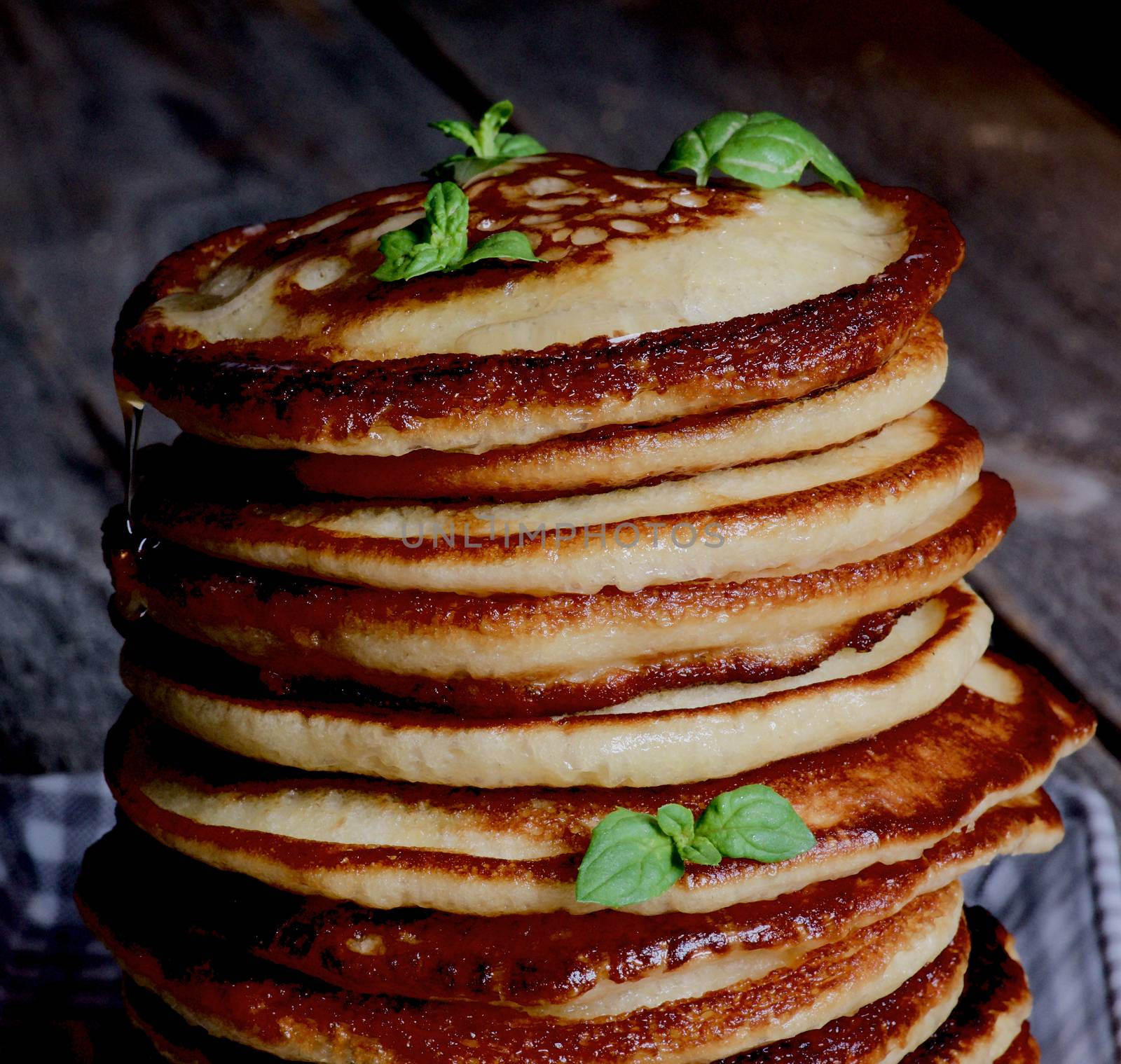 Stack of Delicious Homemade  Pancakes with Glazed Honey and Mint Leafs in Shadow closeup on Wooden background 