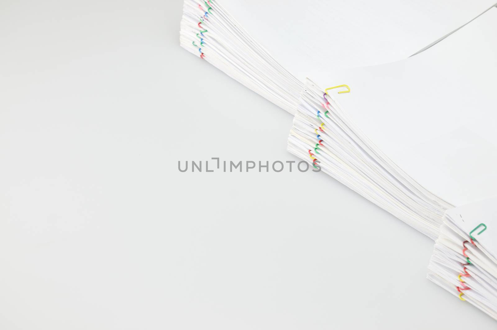 Pile overload document of report and receipt with colorful paperclip place on right with white background.