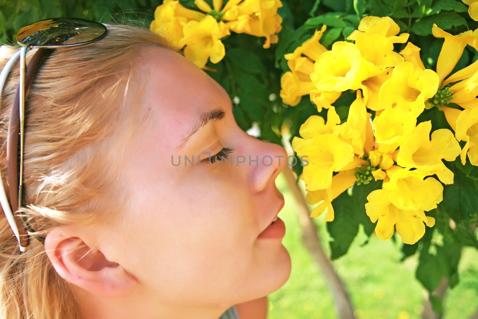 young woman smelling a yellow flower by Tanacha