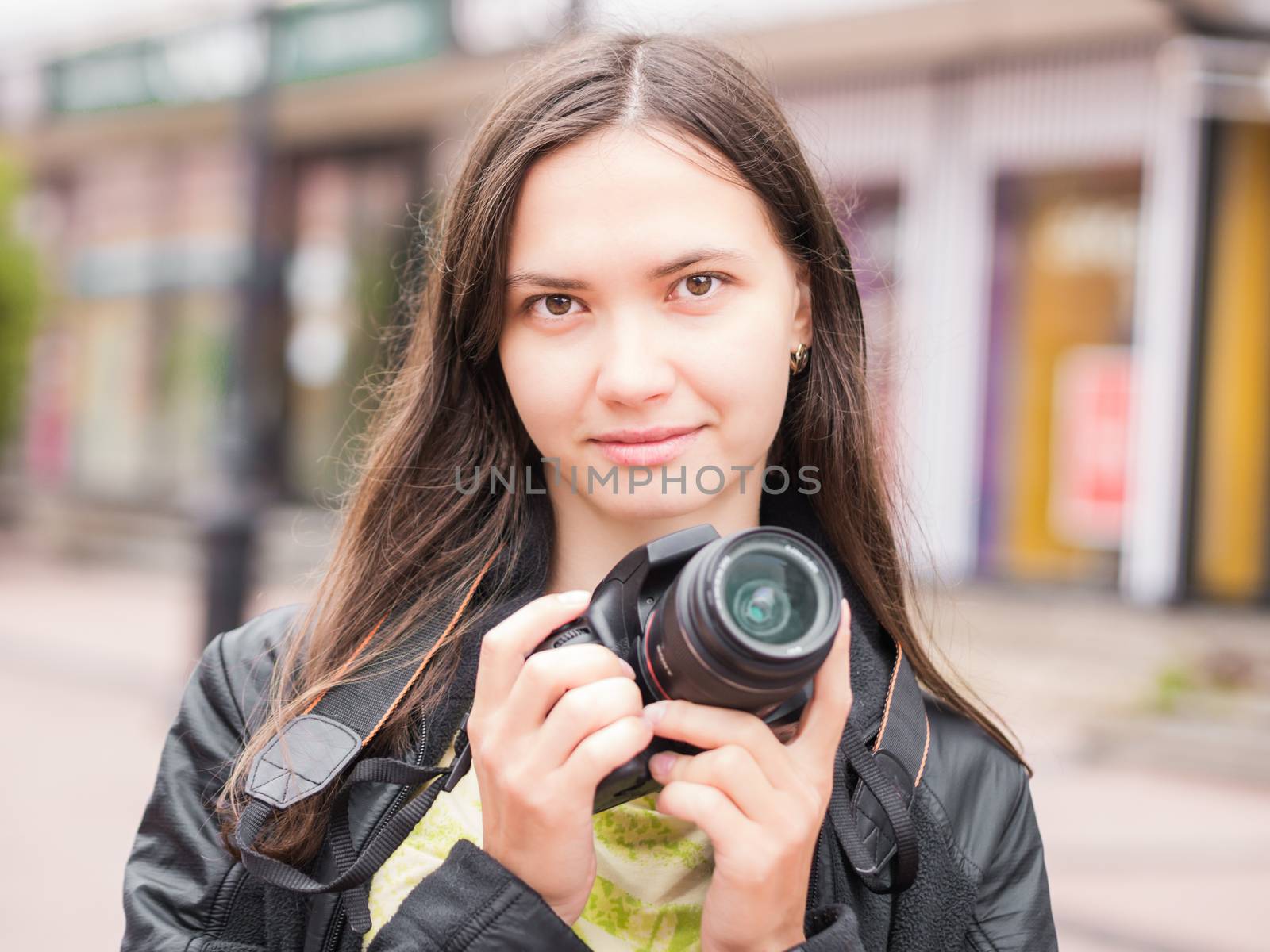 Woman on vacation photographing with dslr camera on city street. Looking at camera. Vacation photography travel concept