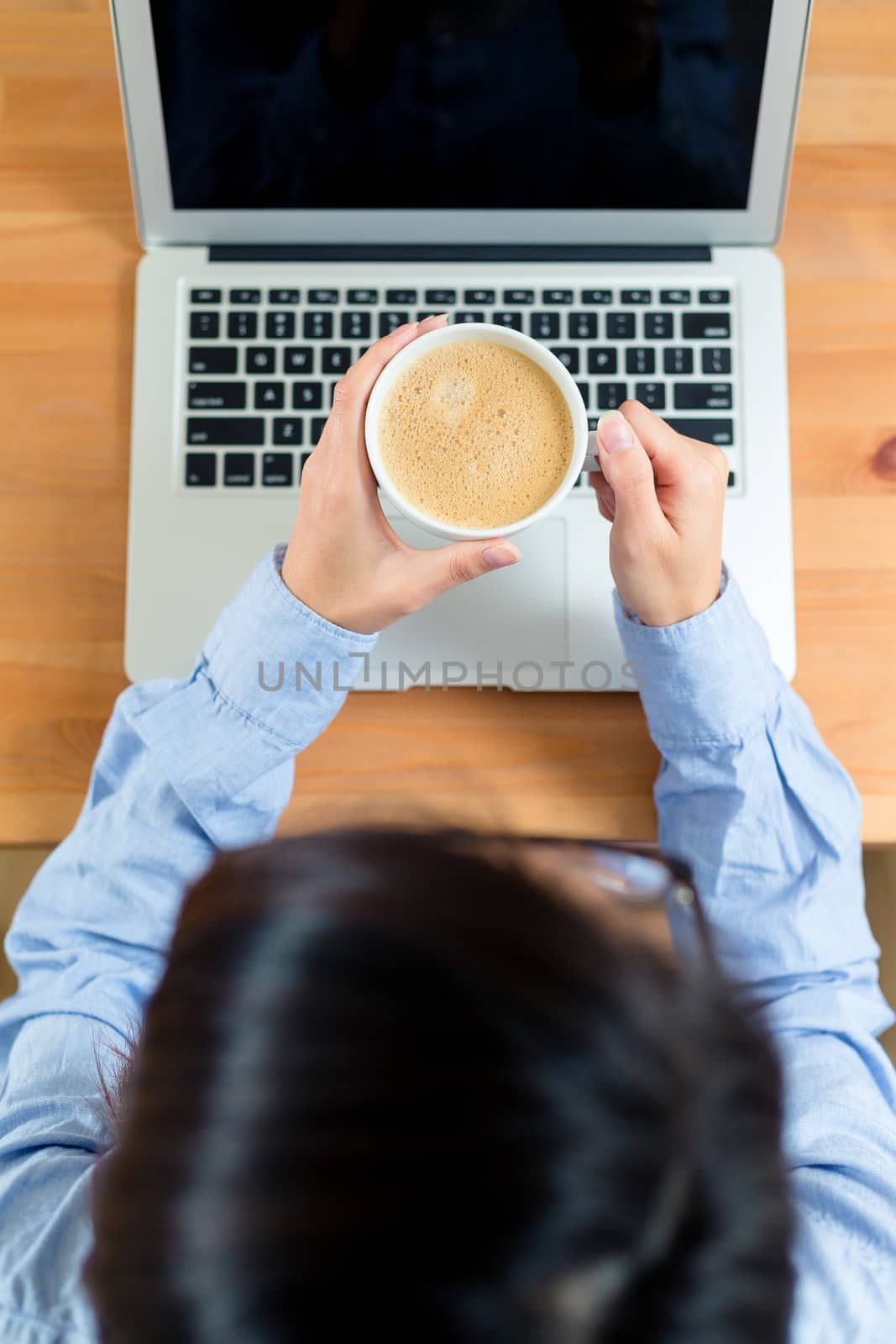 Top view of woman drink of coffee and use of laptop computer by leungchopan