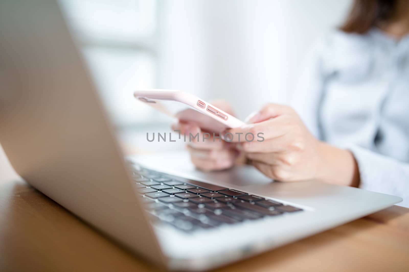 Female hands using modern smart phone while working at office with computer