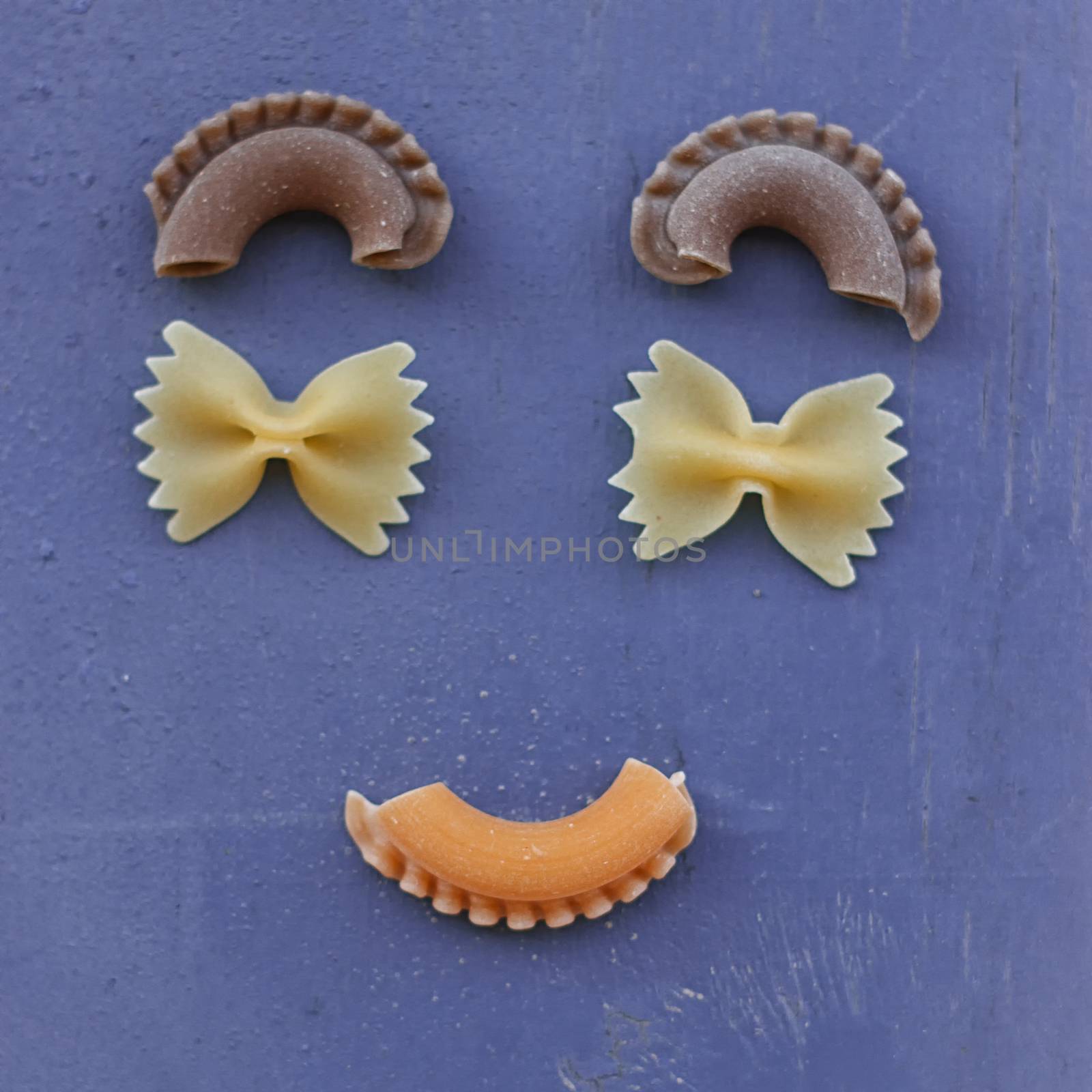 smiley face with raw pasta on blue background