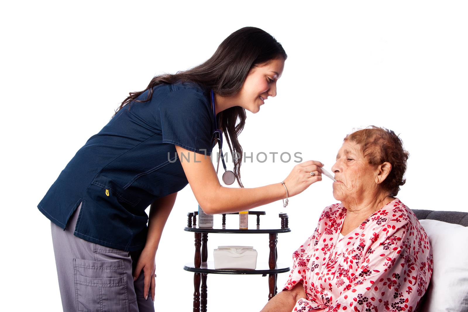 Nurse measuring temperature of senior woman, healthcare home health concept.