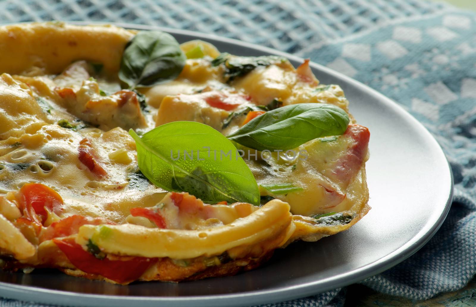 Fluffy Omelet with Vegetables, Greens and Basil Leafs on Grey Plate against Light. Selective Focus