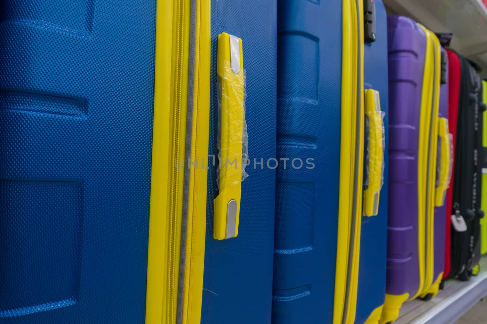 Blue and Yellow suitcases or Travel Bag in a row on shelf in Hypermarket, Shallow Depth of Field.