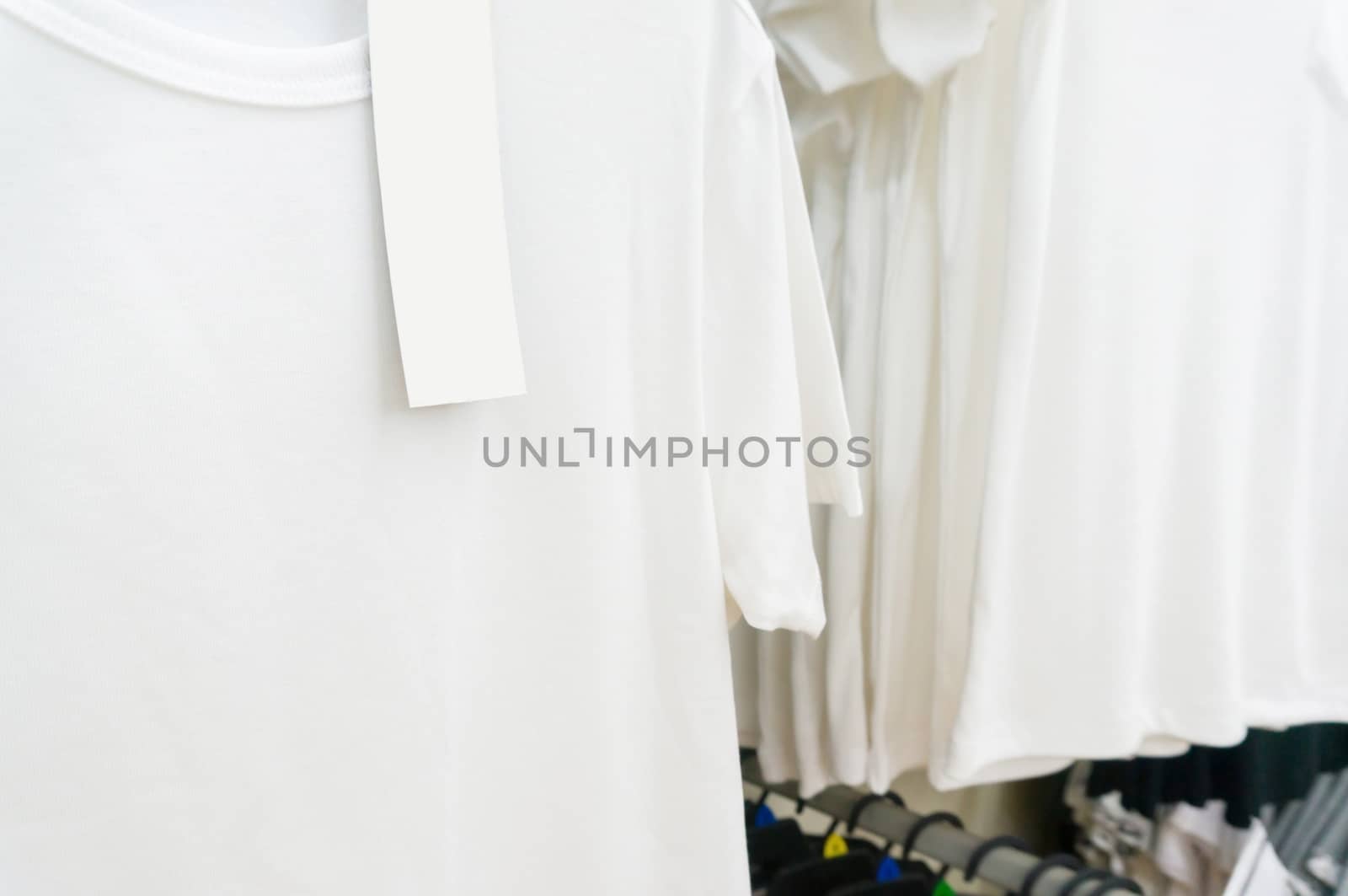 blank price tag hang over white tshirt on Hanger Shelf in Supermarket or Hypermarket Retail Store Outlet, Shallow Depth of Field.