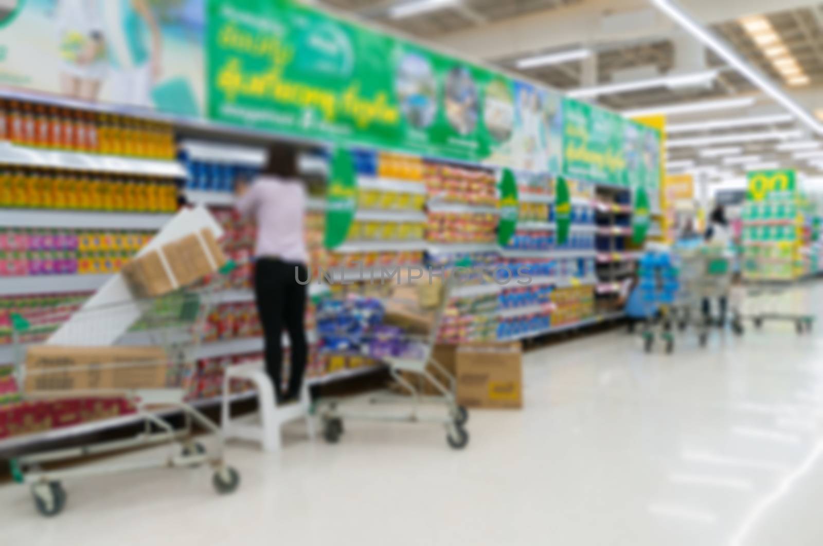 Merchandising. Sales assistant in supermarket arrange goods on supermarket shelves at store, Abstract Blur or Defocus Background