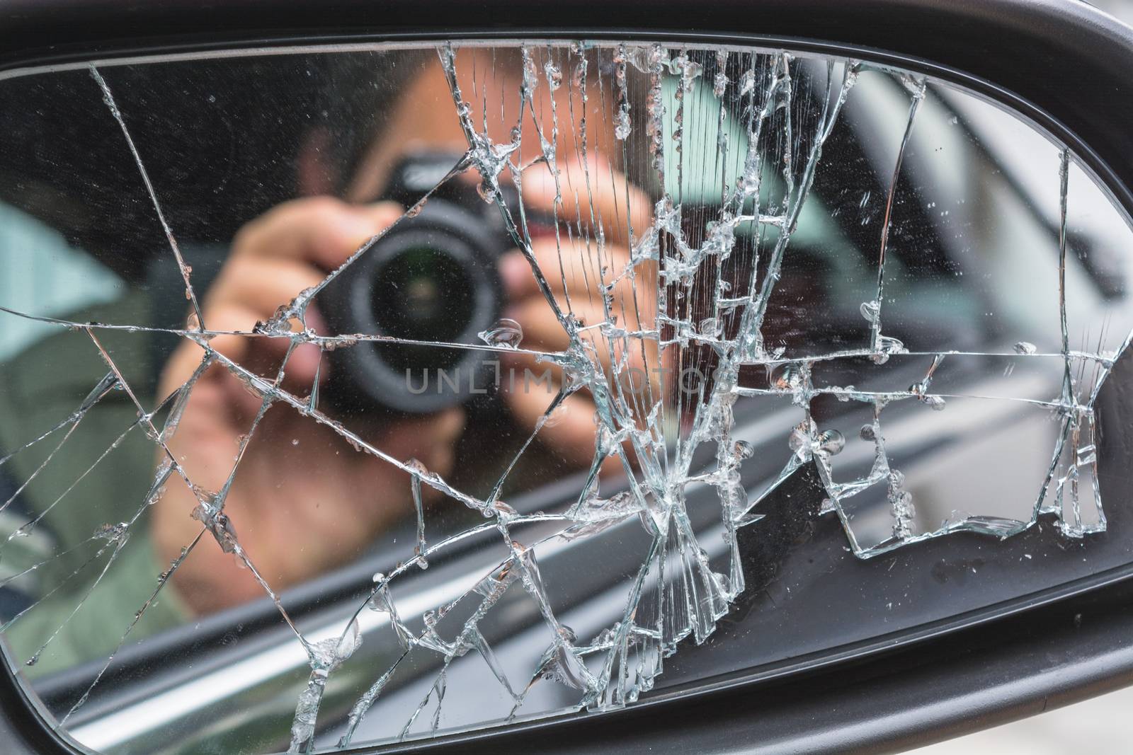 Mirror image of a photographer in the broken car mirror
