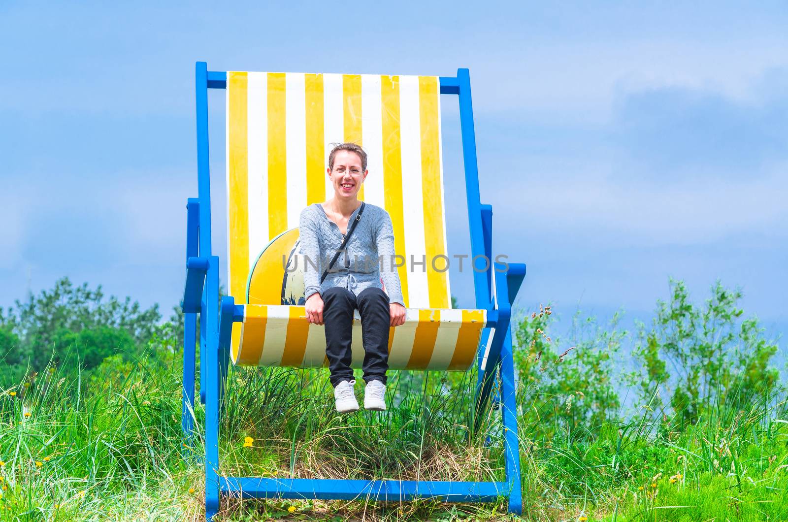 Gigantic deckchair with young women in front of a blue sky.

