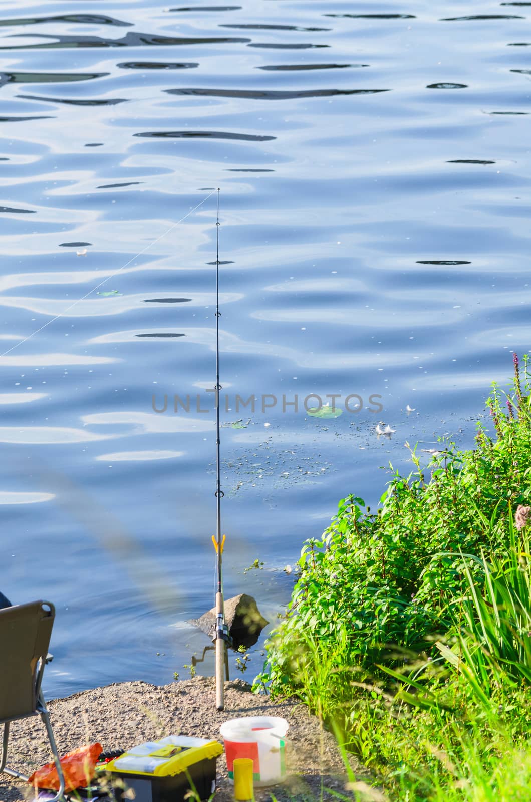 Individual fishing rod on a support with bait in the water.