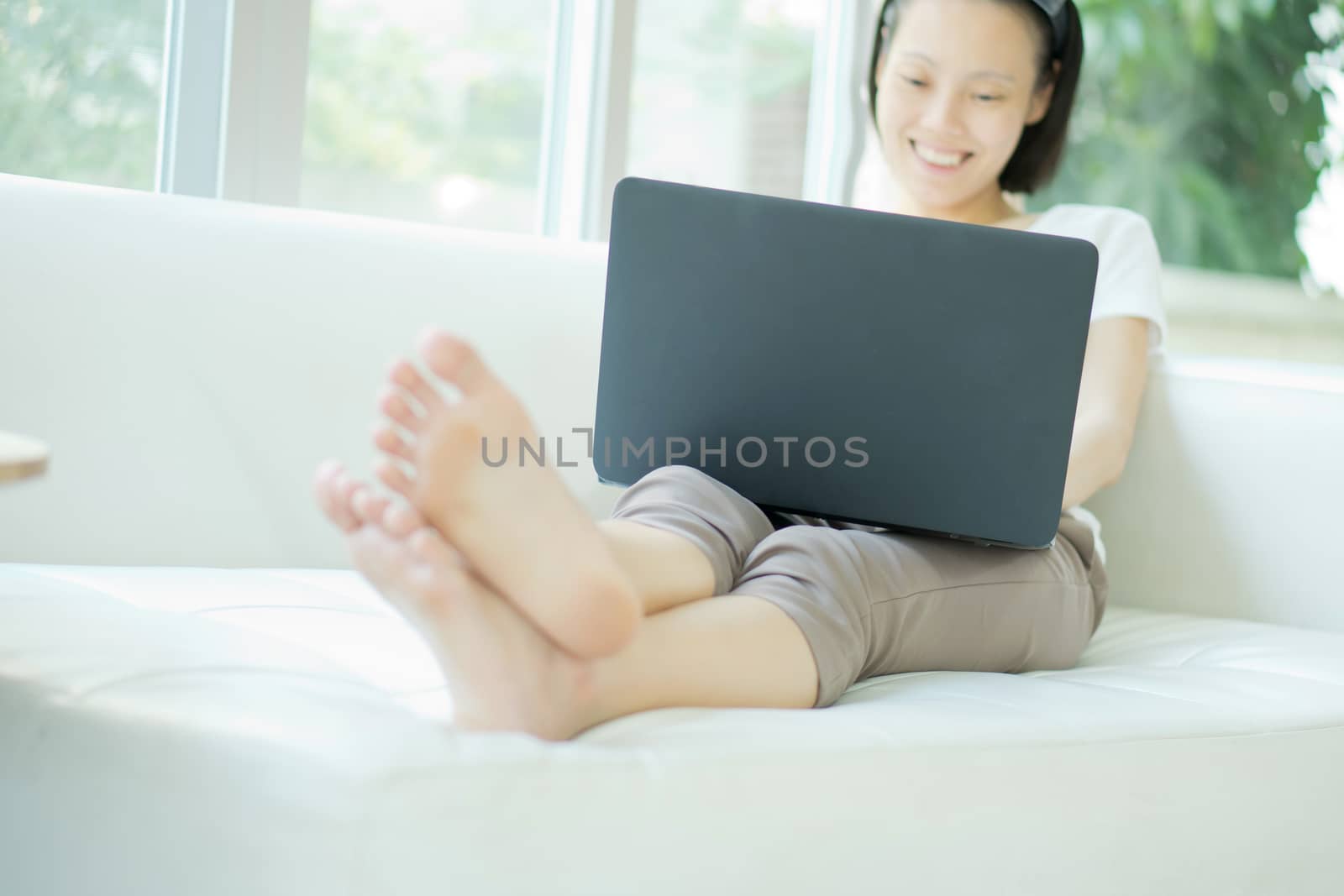 Smiling happy woman sitting on the sofa and using laptop - High  by ekachailo