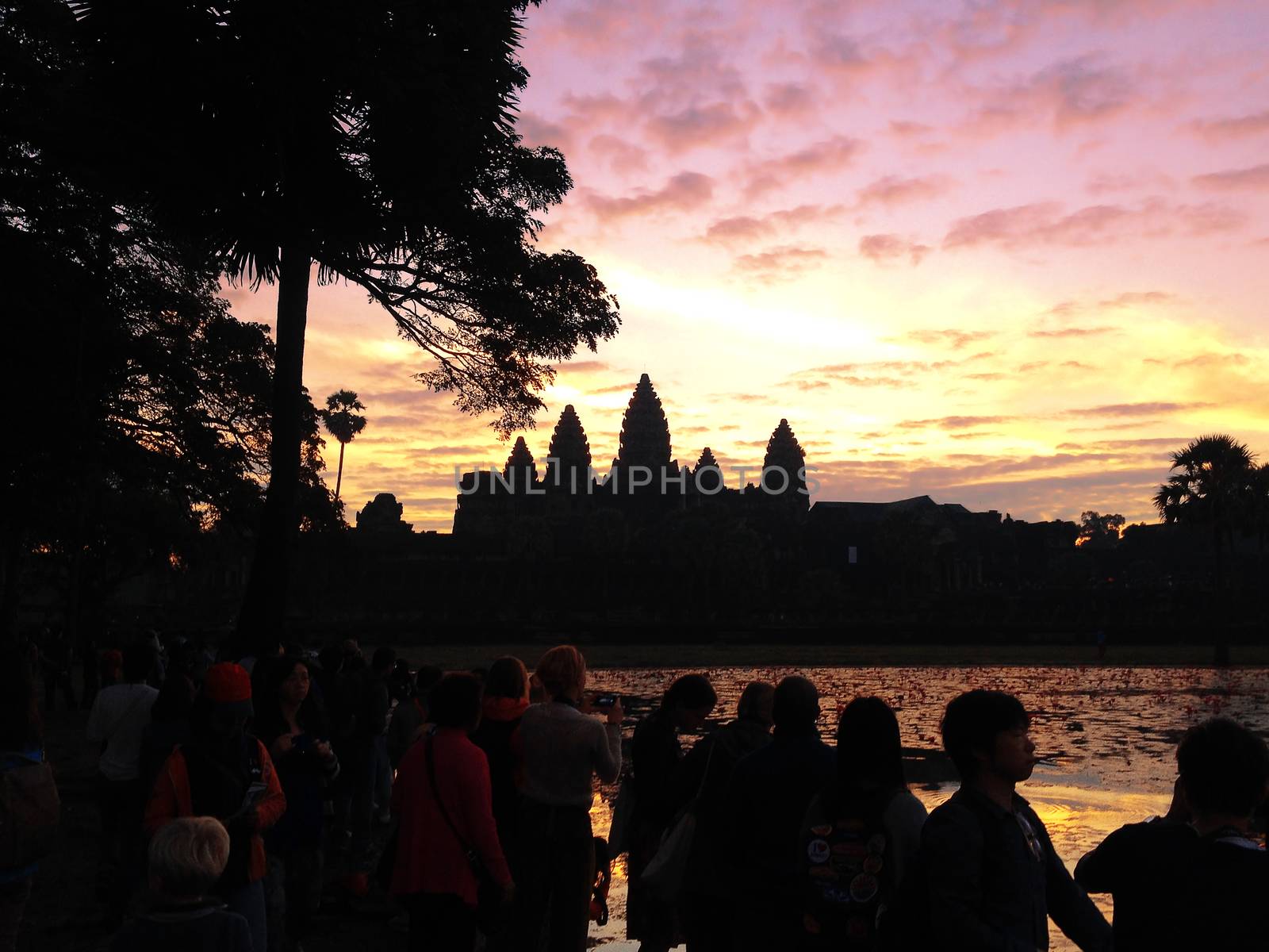 Many Asian tourists taking picture of ancient temple Angkor Wat  by orsor