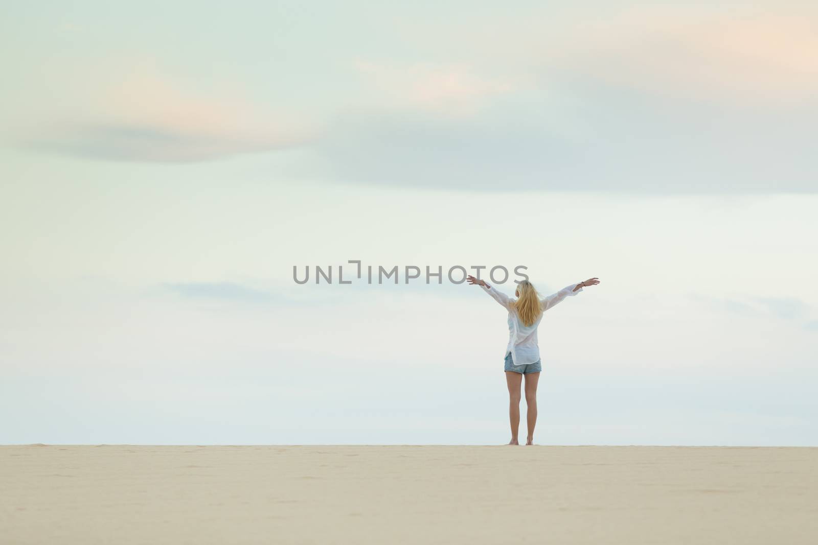 Woman enjoying freedom feeling as a bird at beach at dusk. Serene relaxing woman in pure happiness and elated enjoyment with arms raised outstretched up. 