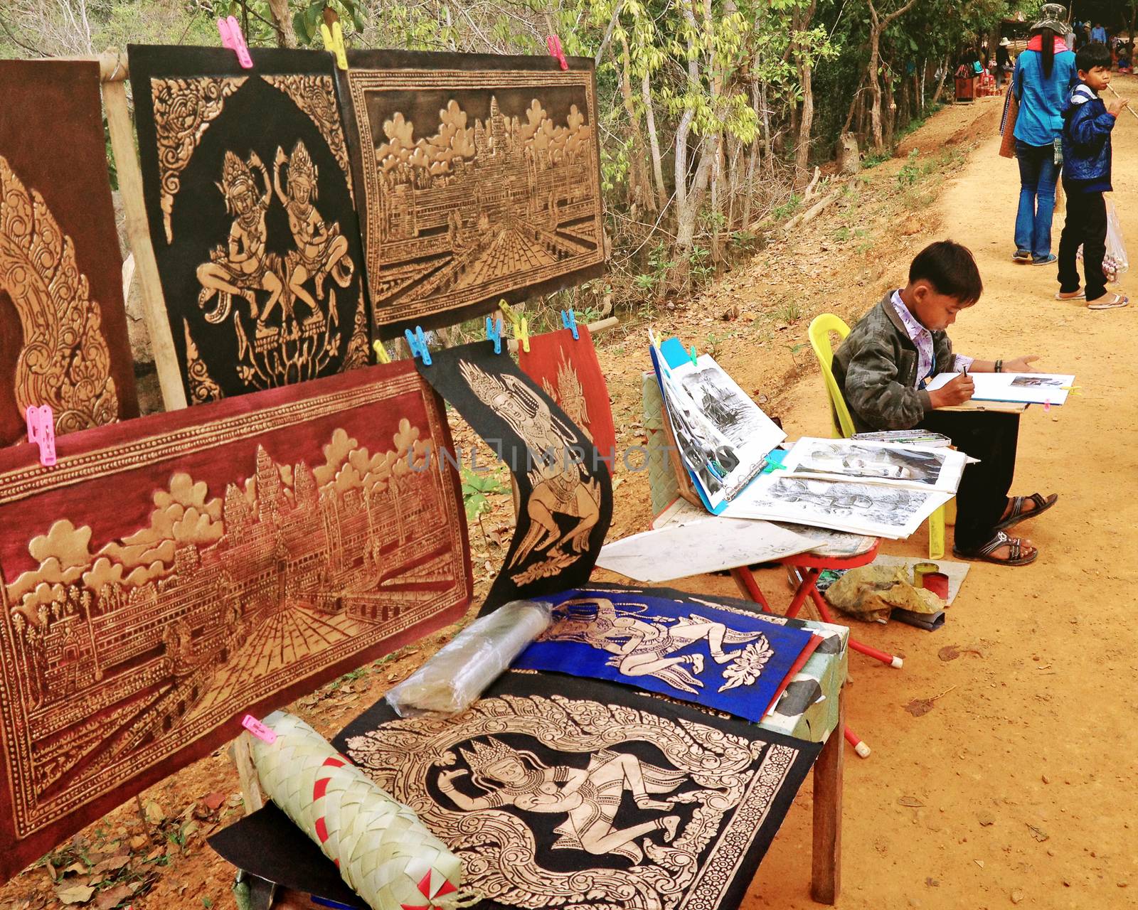 SIEM REAP, CAMBODIA - December 22, 2013 : Young artist at work painting at Neak Pean Temple area in Siem Reap. Cambodia.