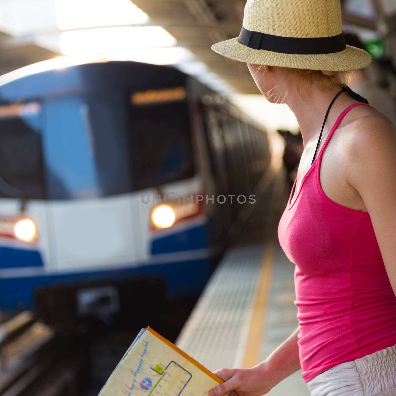 Young woman with a map in her hand waiting on the platform of a railway station for their train. to arrive.