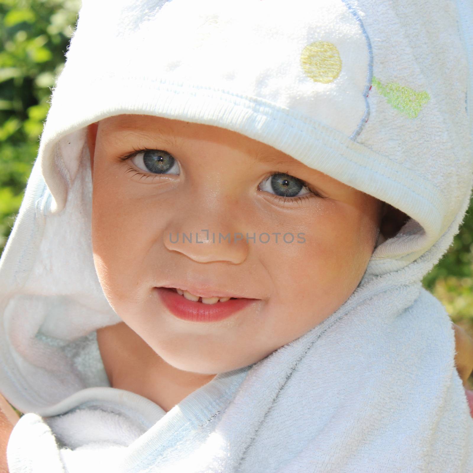 Closeup portrait of cute smiling baby boy in blue towel