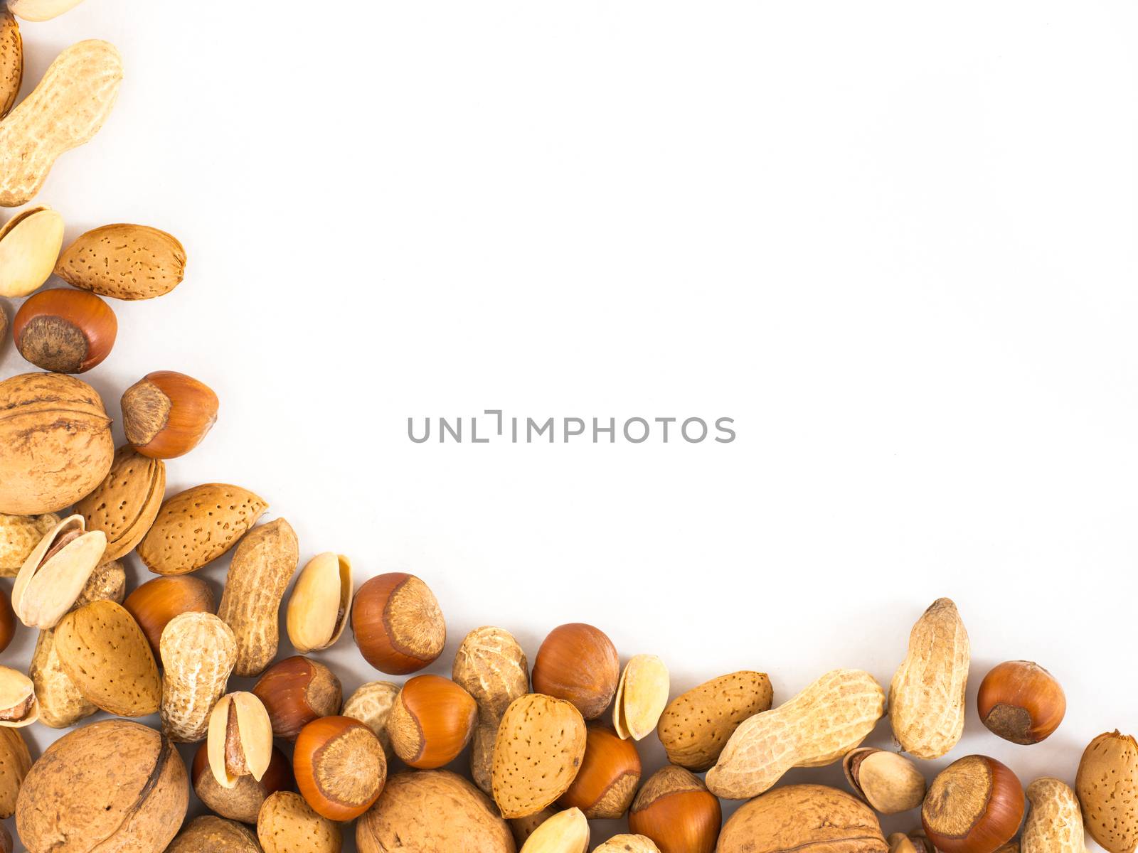 Background of mixed nuts in shell - hazelnuts, almonds, walnuts, pistachios, peanuts not peeled - with copy space. Isolated one edge. Top view or flat lay