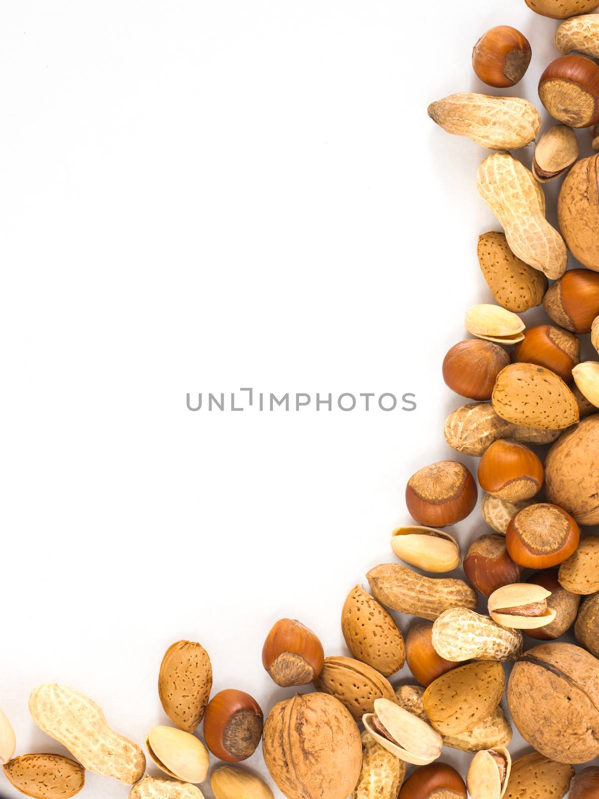 Background of mixed nuts in shell - hazelnuts, almonds, walnuts, pistachios, peanuts not peeled - vertical with copy space. Isolated one edge. Top view or flat lay