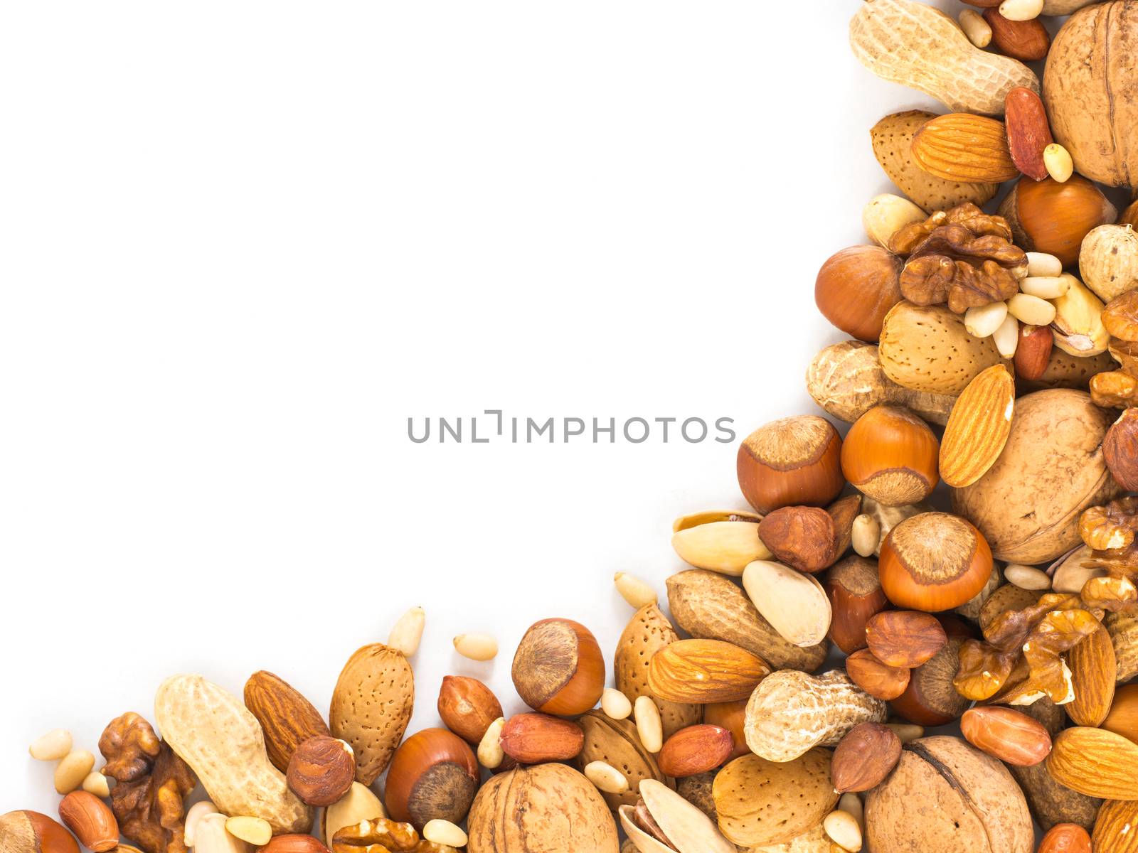 Background of mixed nuts - hazelnuts, almonds, walnuts, pistachios, peanuts, pine nuts peeled and not peeled - with copy space. Isolated one edge. Top view or flat lay