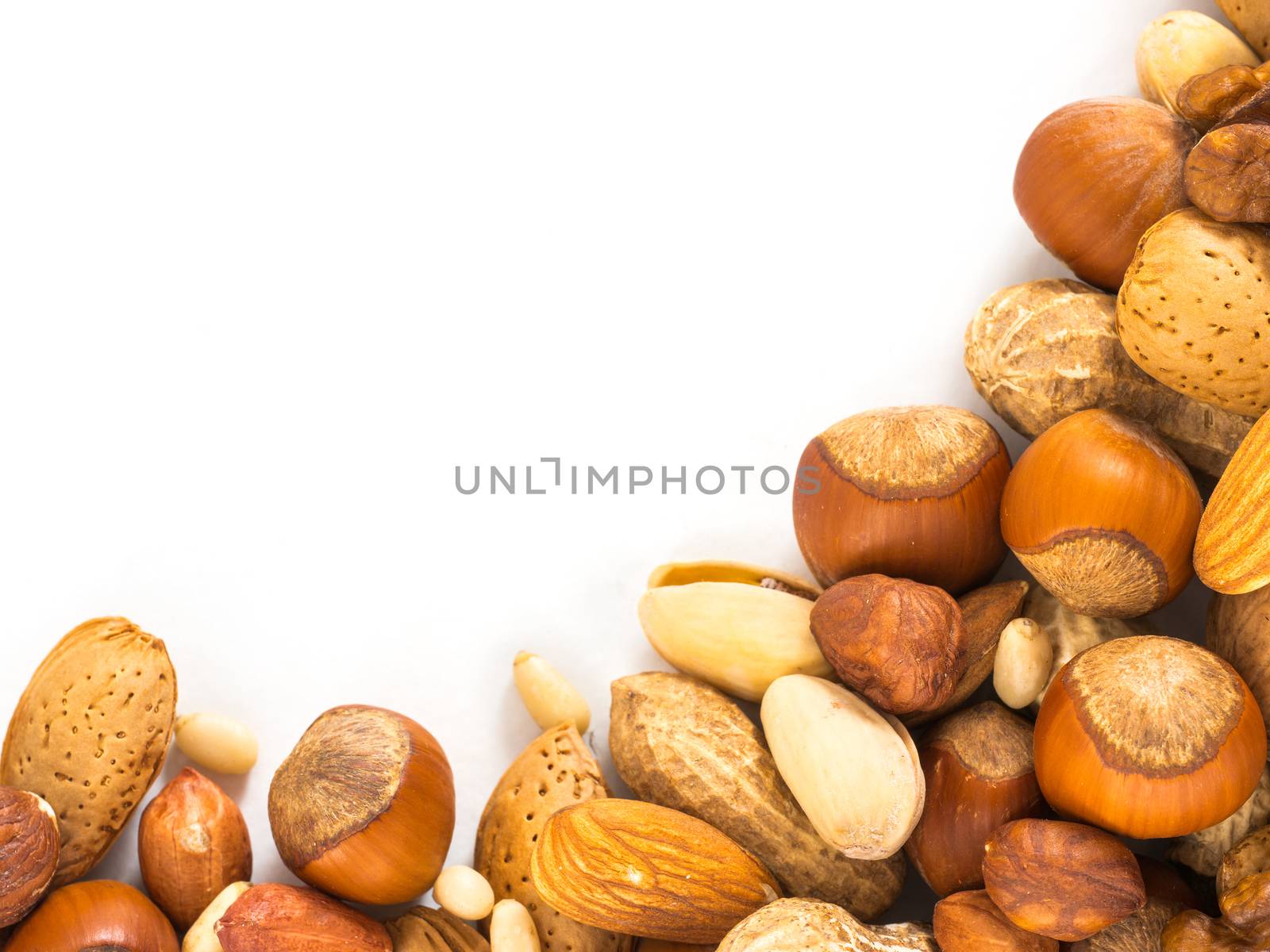 Background of closeup mixed nuts - hazelnuts, almonds, walnuts, pistachios, peanuts, pine nuts peeled and not peeled - with copy space. Isolated one edge. Top view or flat lay