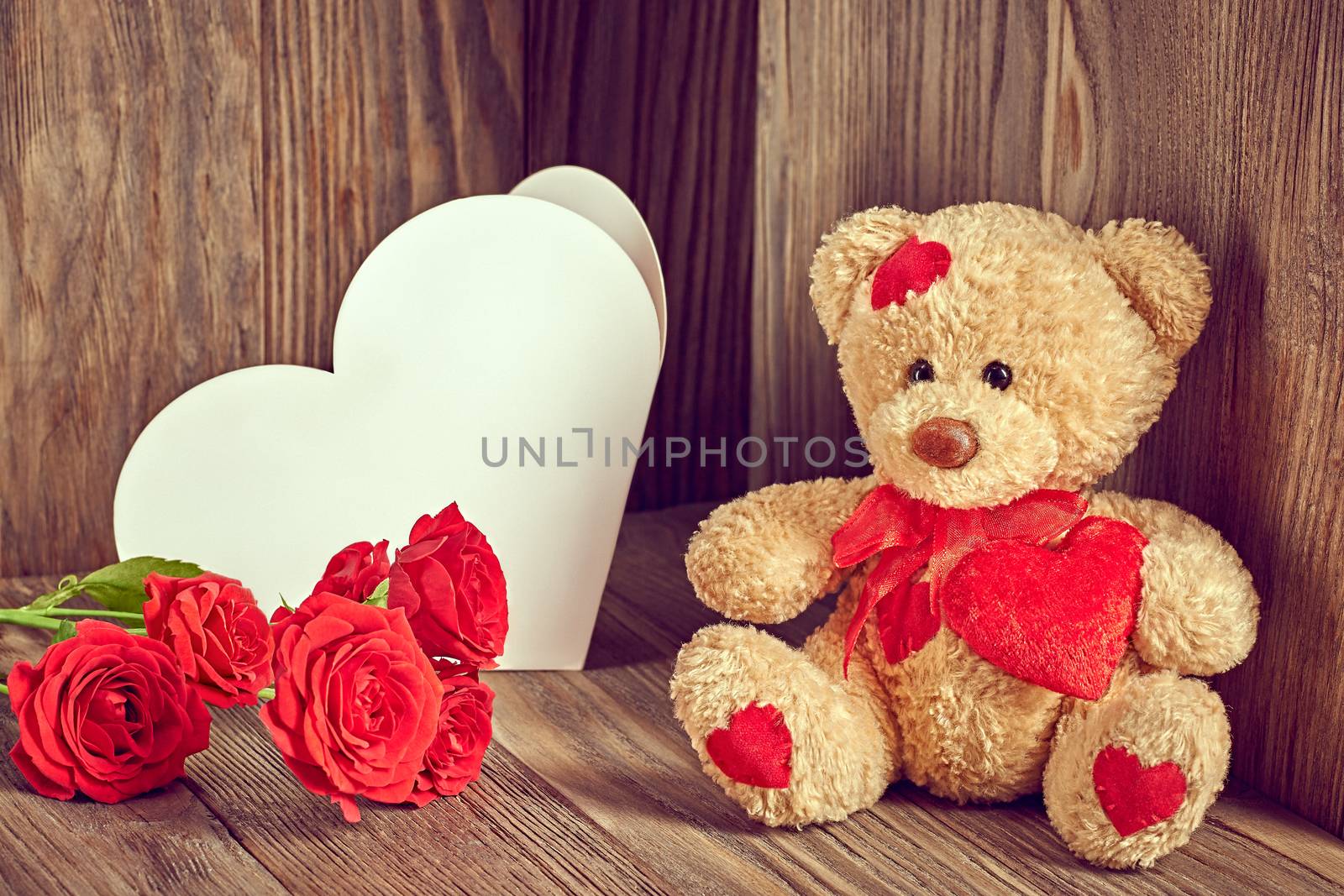 Valentines Day. Teddy Bear Loving with red hearts sitting alone. Note and bouquet of red roses. Vintage. Retro romantic styled on wooden background. Copyspase