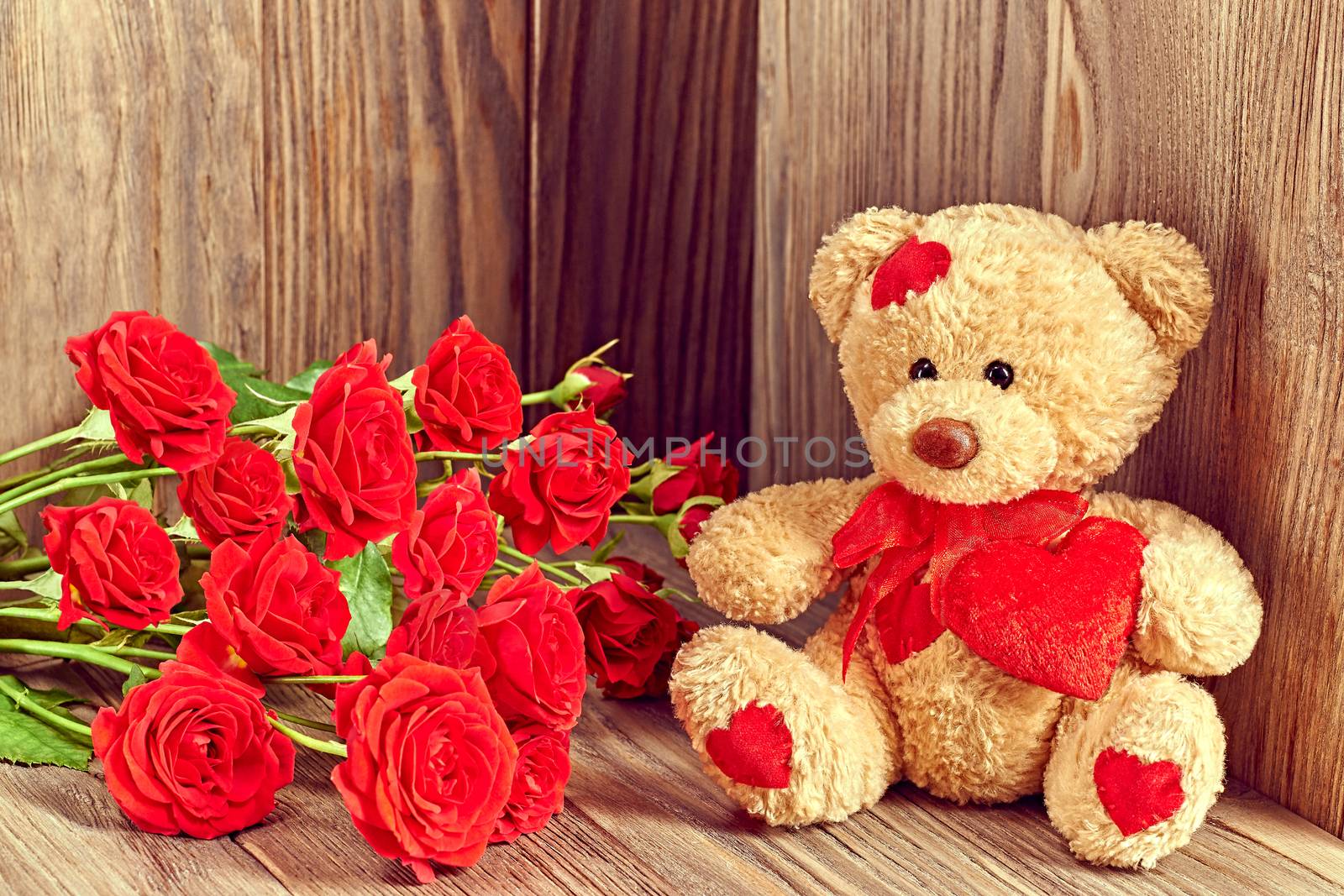 Valentines Day. Teddy Bear Loving cute with red hearts sitting alone with bouquet of red roses. Vintage. Retro romantic styled on wooden background. Copyspase