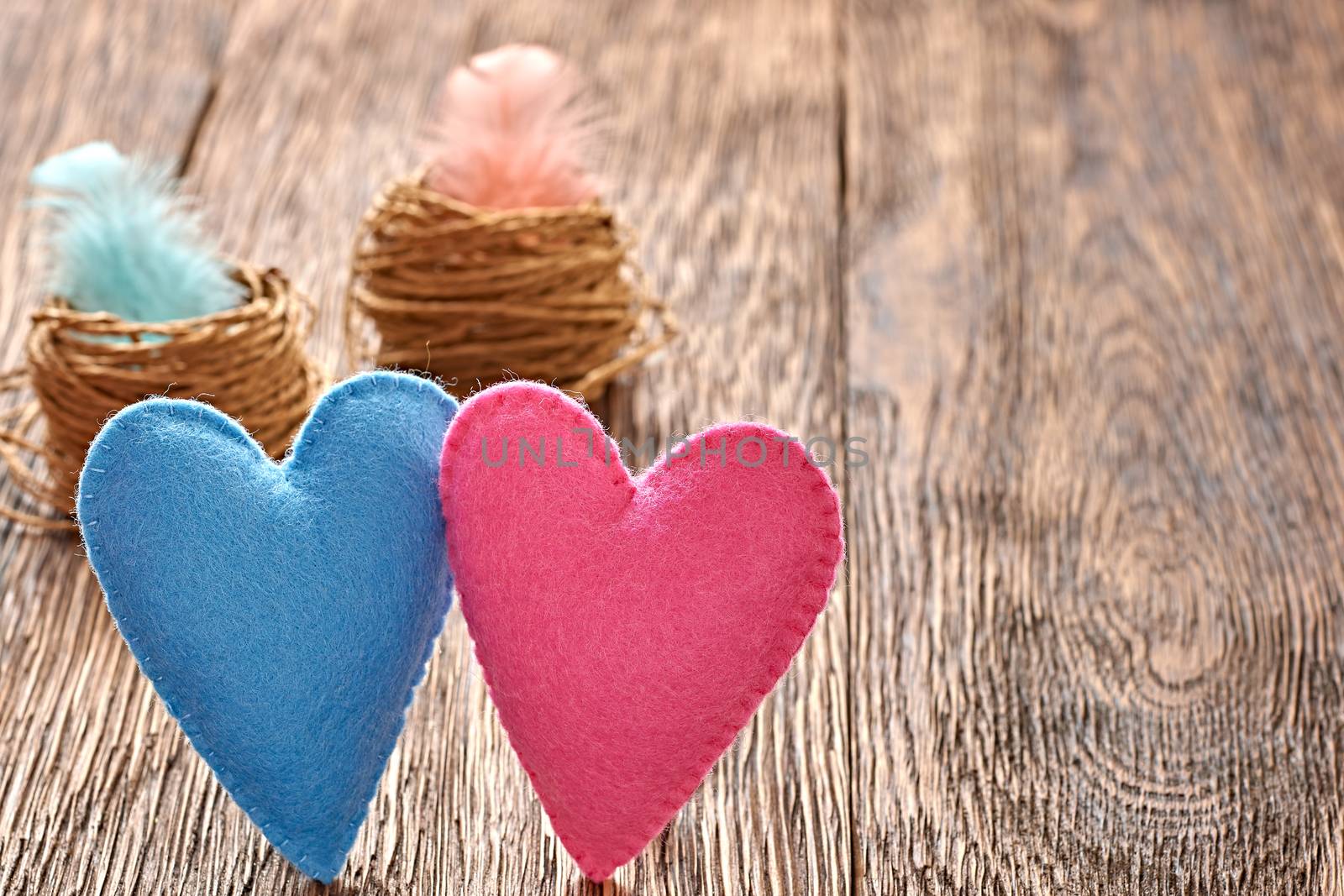Love, Valentines Day. Hearts couple Handmade and nests with feathers on wooden background. Vintage romantic style. Vivid unusual creative greeting card, multicolored felt. Toned