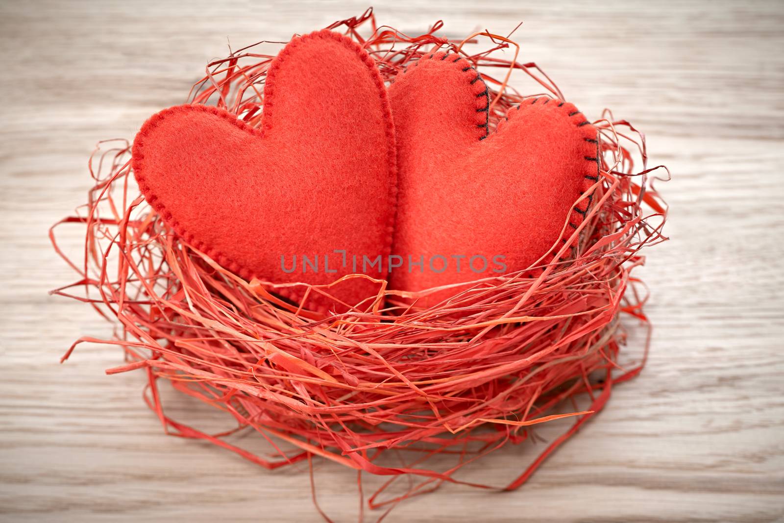 Love hearts, Valentines Day. Hearts handmade on wooden background. Couple made of red felt in straw nest. Vintage romantic style. Vivid greeting card.  